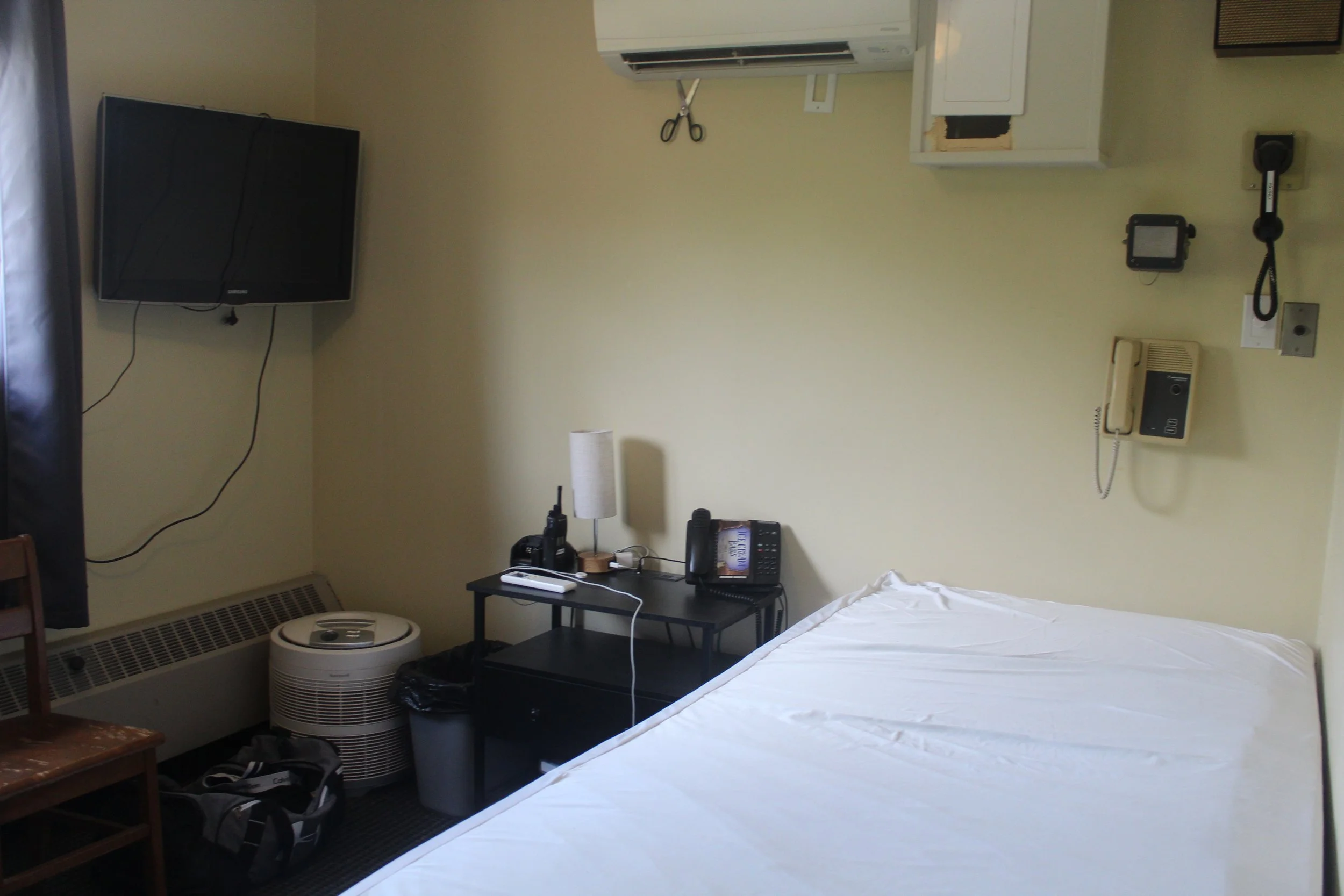 One of the dorm rooms in Fire Station 1 with a bed, side table and television