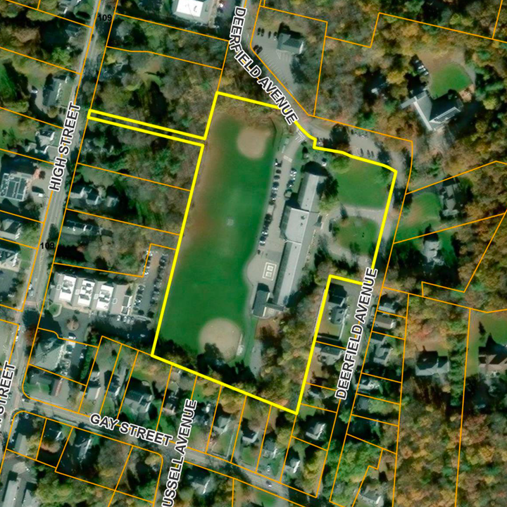 Aerial view of a school with a baseball field and football field, surrounded by residential neighborhoods with streets named Gay Street, High Street, and Deerfield Avenue.