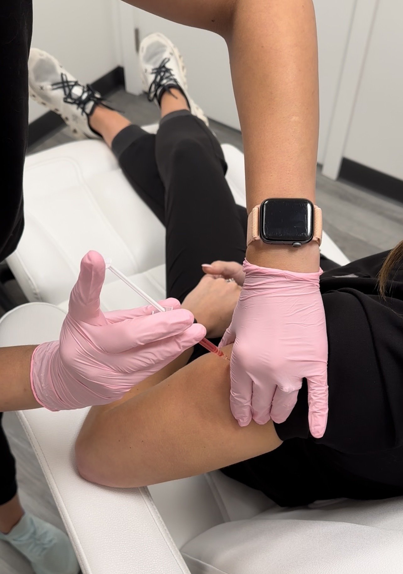 A person receiving a vitamin b shot in their upper arm from a healthcare worker wearing pink gloves.