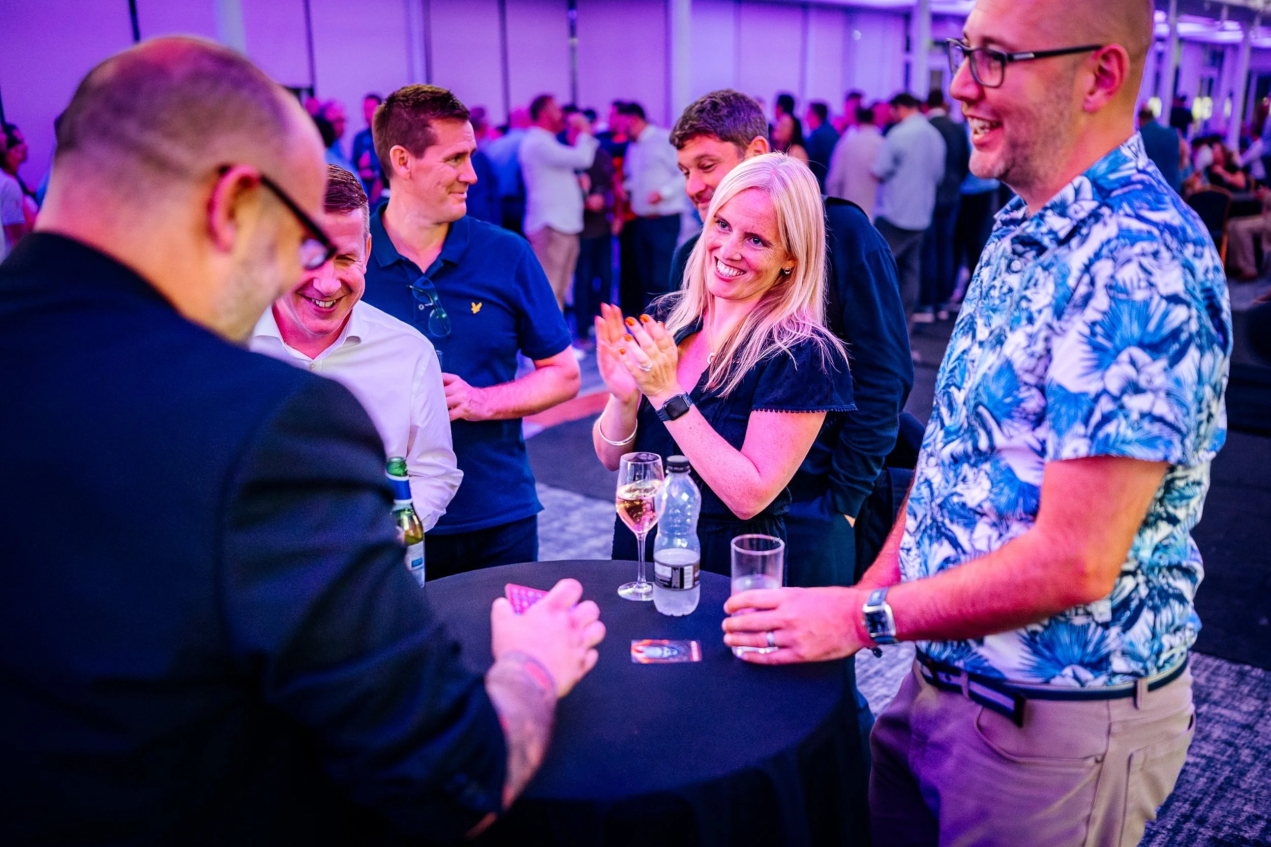 A close-up candid capture of a corporate magician entertaining guests at a high-top table during the evening reception of the Midwich Tech Xpo, Ascot. Experiential corporate entertainment photography by Will Bailey.