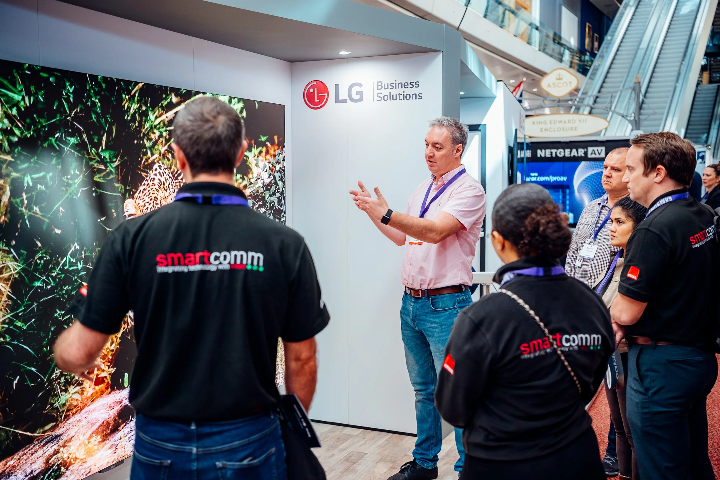 Industry delegates discussing smart communications at the LG Business Solutions exhibition stand during the Midwich Tech Xpo at Ascot. Tech trade show and sponsor photography by Will Bailey.