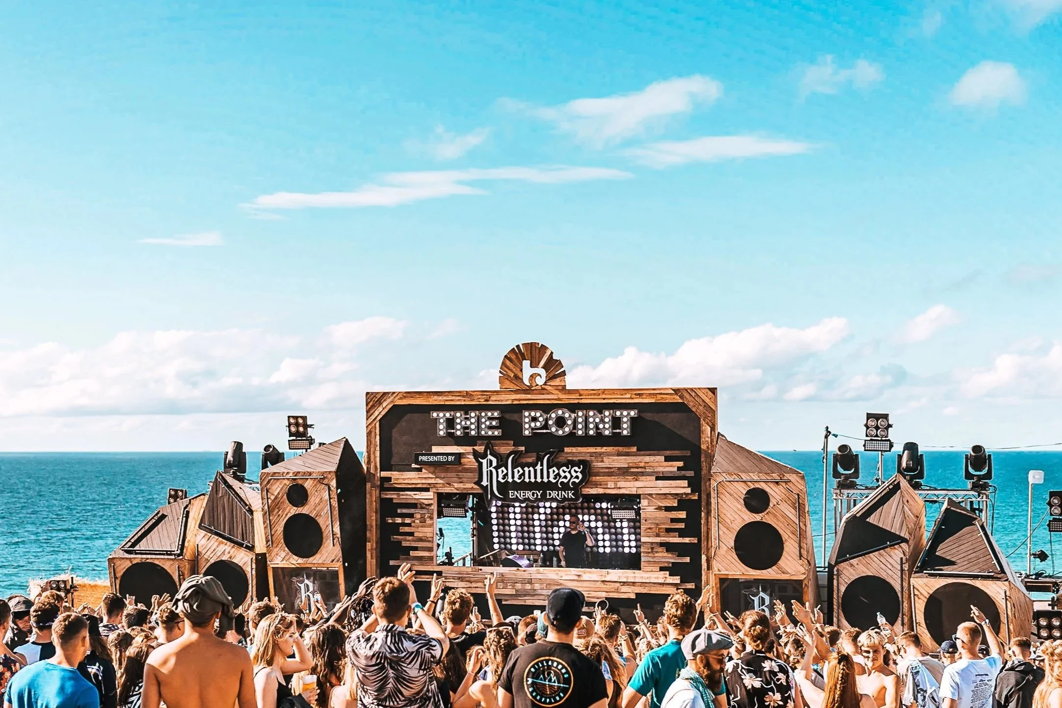 Ocean-view electronic stage photography of The Point presented by Relentless at Boardmasters Festival in Cornwall, capturing a DJ performing to a coastal crowd, by Will Bailey.