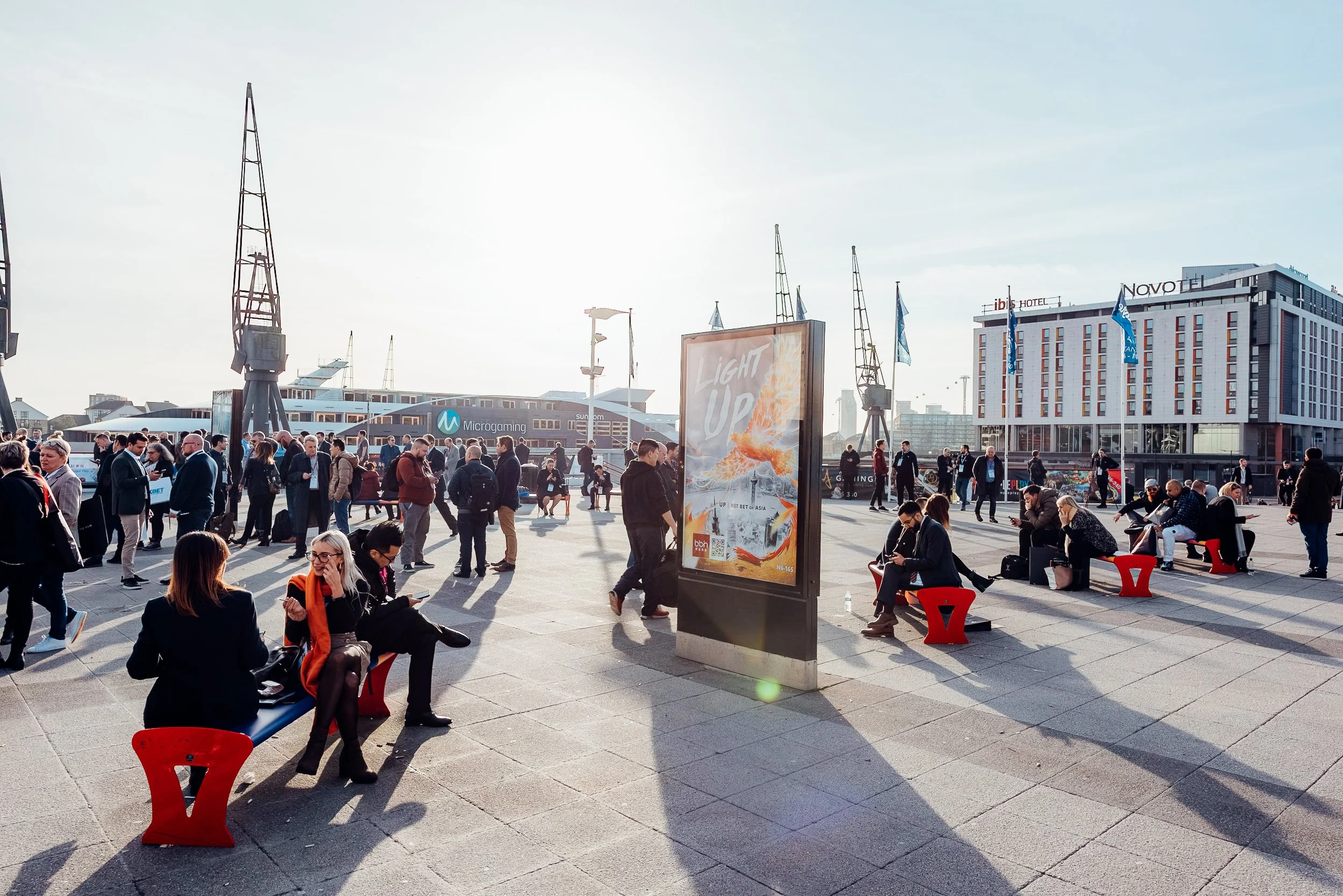 Outdoor commercial branding and attendee foot traffic for BBIN on the waterfront plaza outside ExCeL London during the ICE London expo. Premium corporate event and sponsorship photography by Will Bailey.