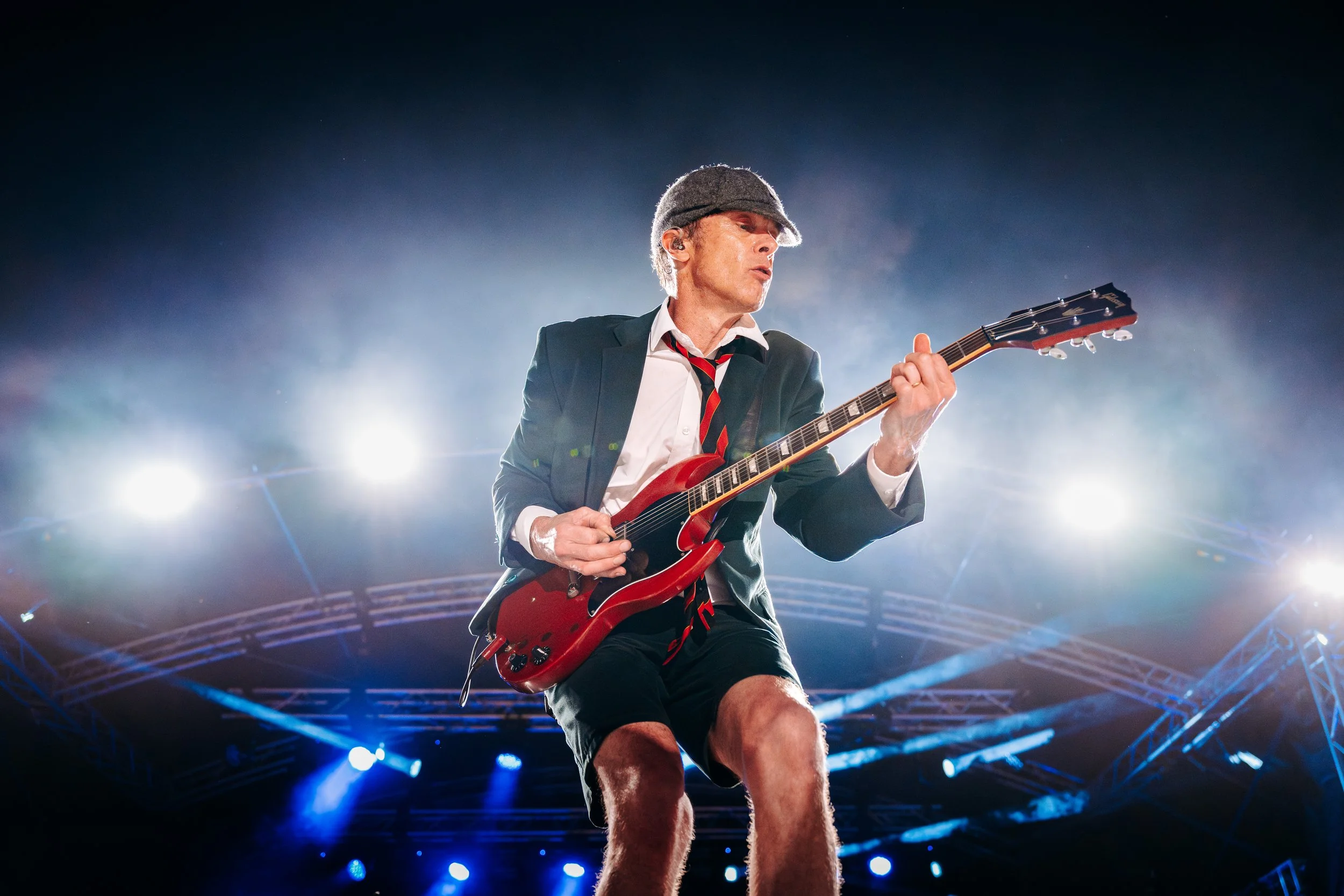 The lead guitarist of tribute act AC/DC UK's high-energy on stage in full school uniform attire during the Rock n Ribs Festival. High-octane rock tribute act and summer festival action photography by Will Bailey.