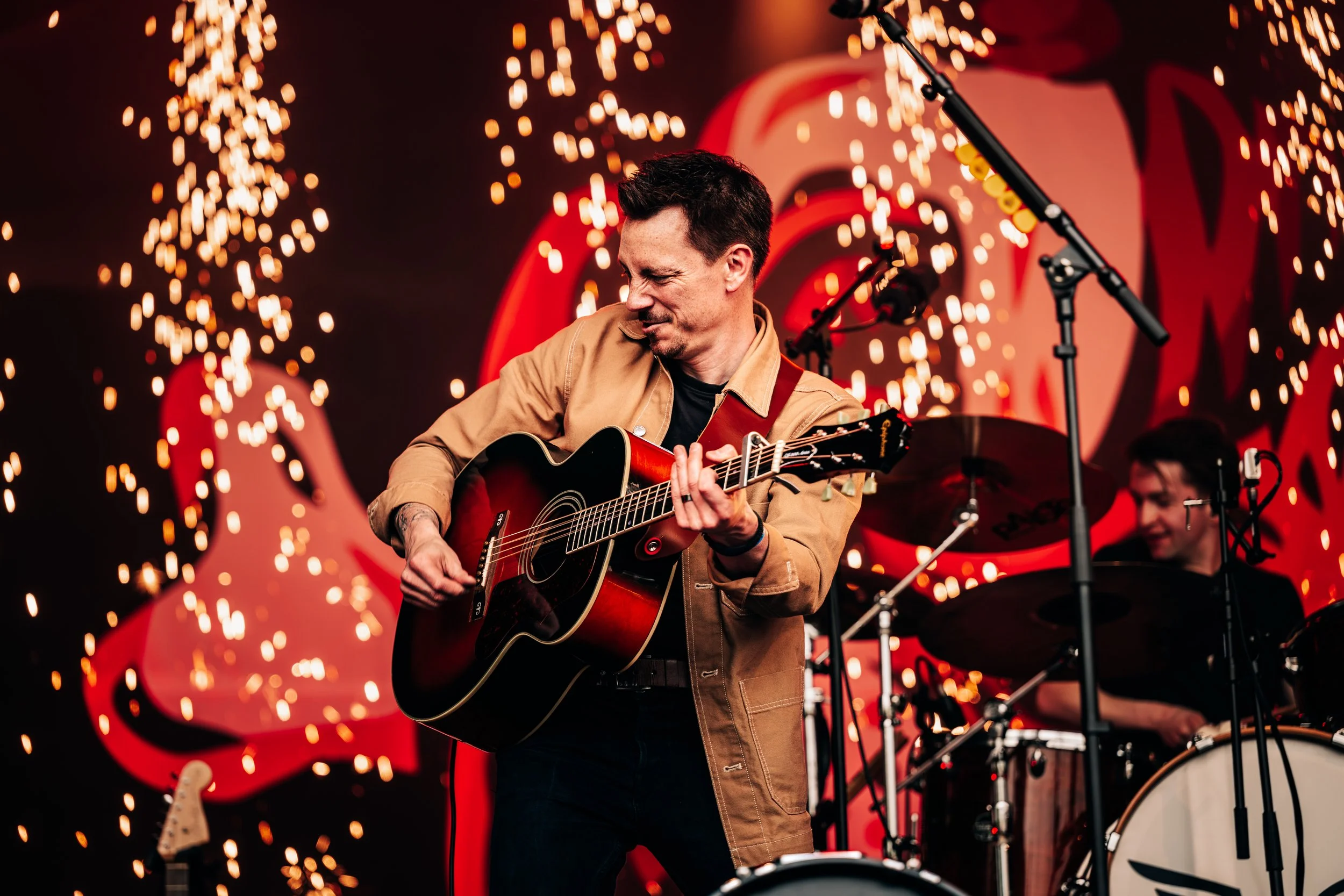 Acoustic folk tribute band Chasing Mumford performing live on stage surrounded by a dramatic curtain of cold spark pyrotechnics at the Teddy Rocks Festival. High-action music festival stage performance and entertainment photography by Will Bailey.