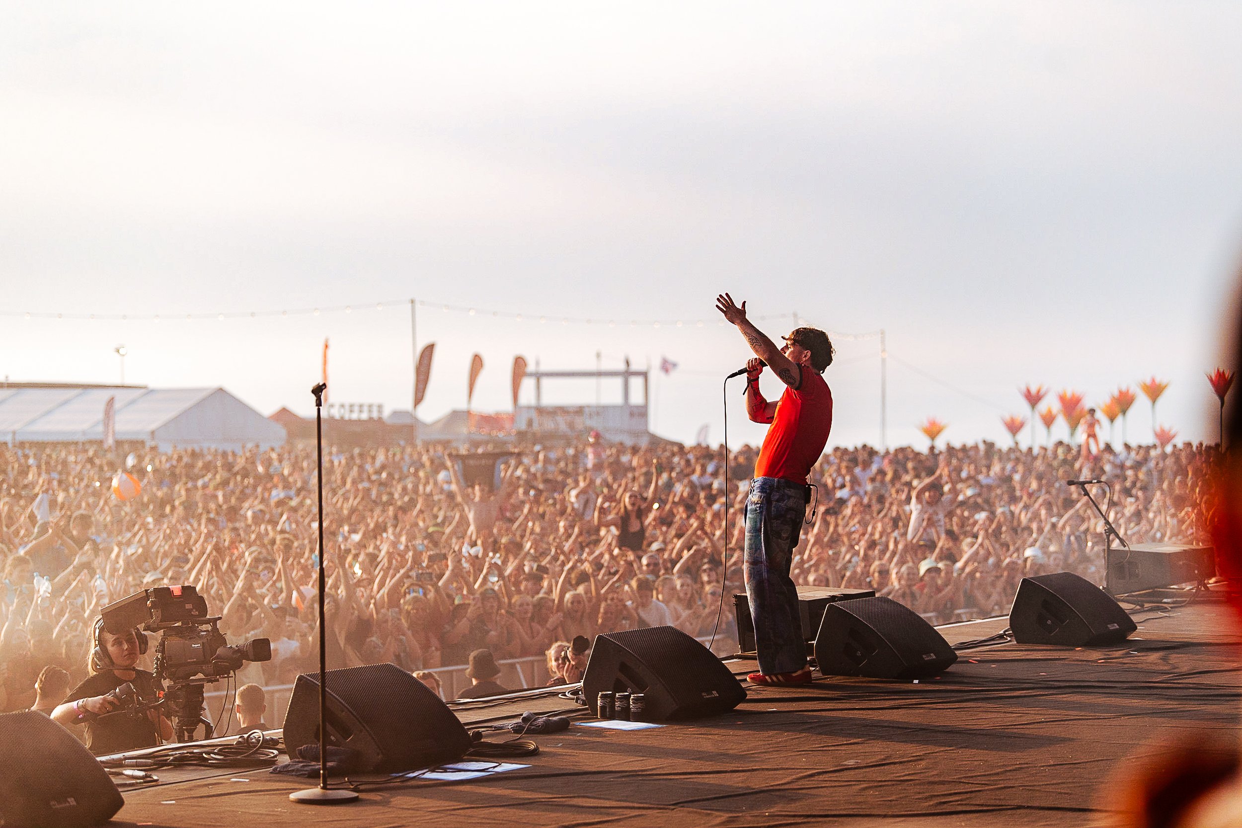Festival main stage photography of singer Tom Grennan performing live during sunset at Boardmasters Festival in Cornwall, engaging a massive outdoor crowd, shot by Will Bailey.