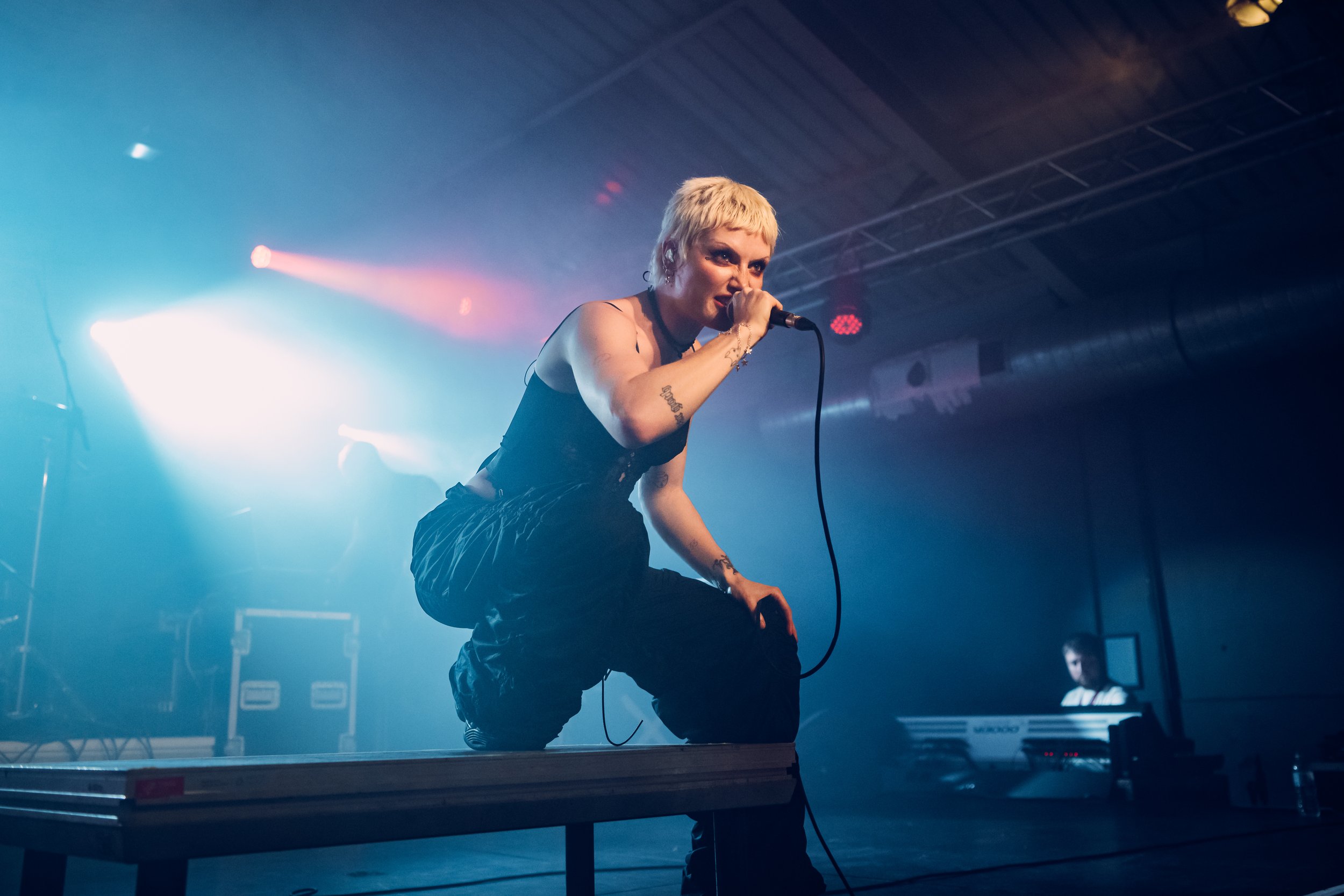 Alternative metal artist Cassyette crouching on a stage riser during a high-octane headline set at a major live stage in Southampton, Hampshire. Intimate club venue concert and UK alternative music scene photography by Will Bailey.