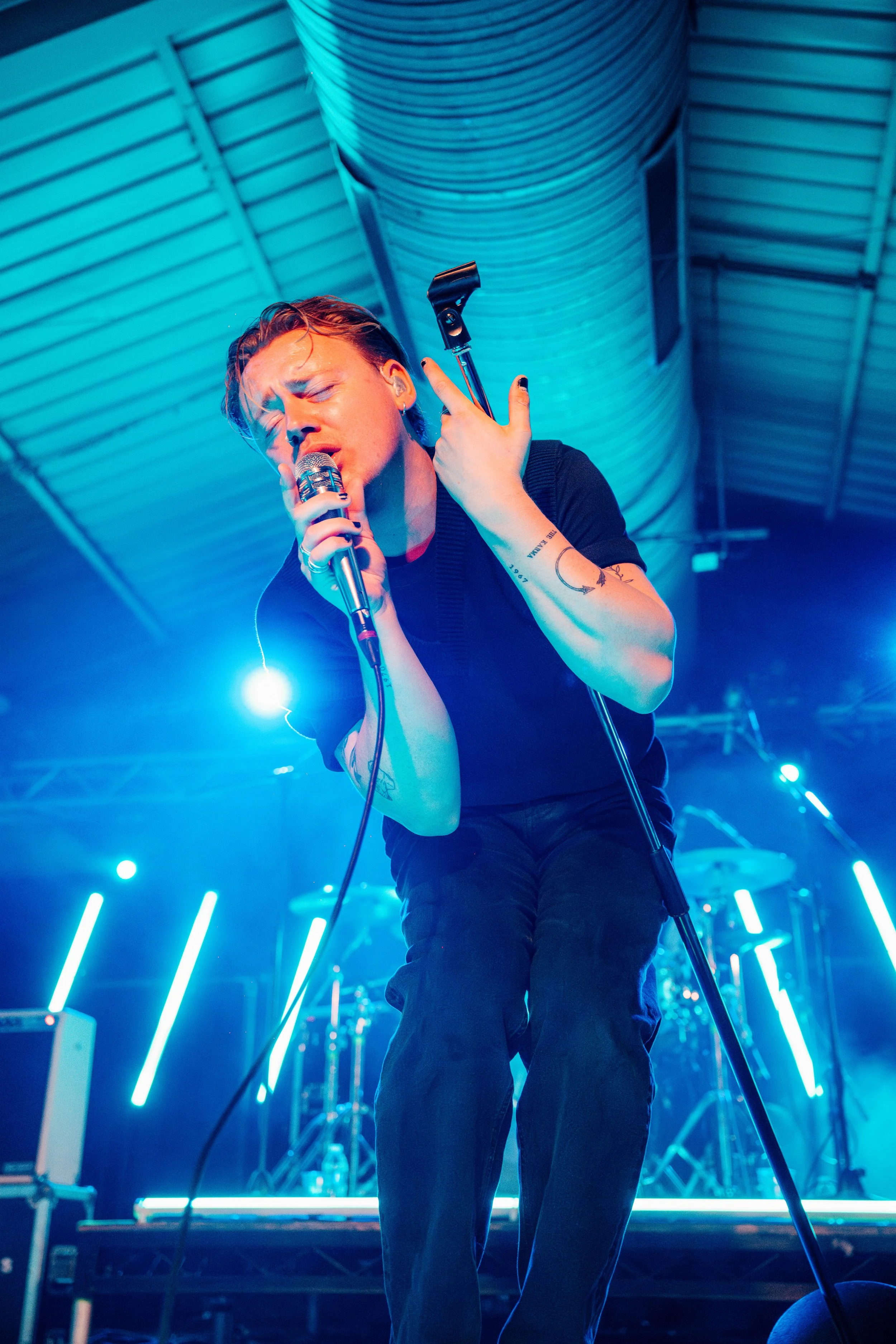 The lead singer of indie pop group Only The Poets performing passionately on stage under intense blue lights at a popular live music venue in Southampton, Hampshire. Professional band promotion and touring artist photography by Will Bailey.