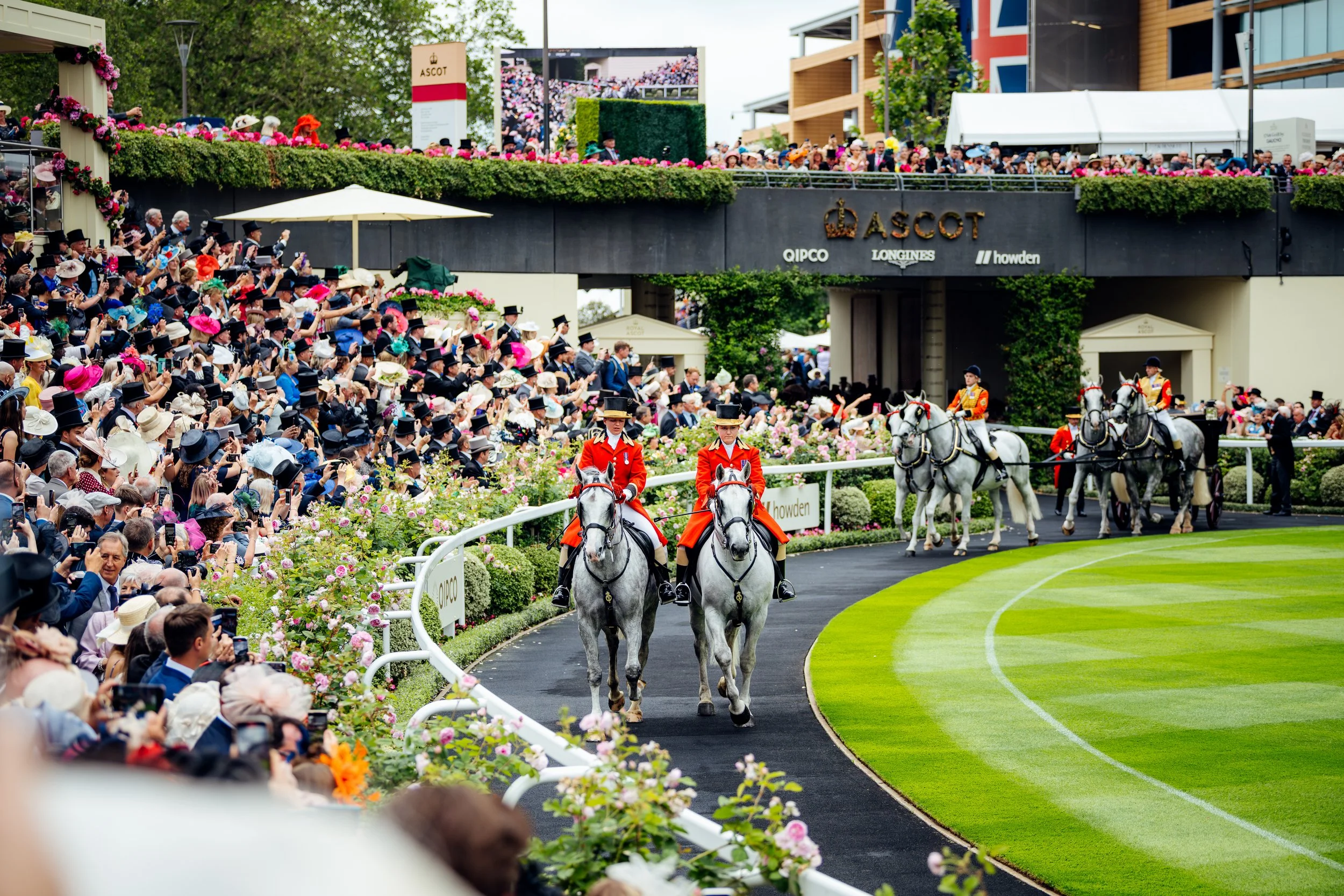 Outriders in traditional scarlet coats leading the Royal Procession carriages into the parade ring at Ascot Racecourse, Berkshire. Elite British heritage and prestigious seasonal sports event photography by Will Bailey.