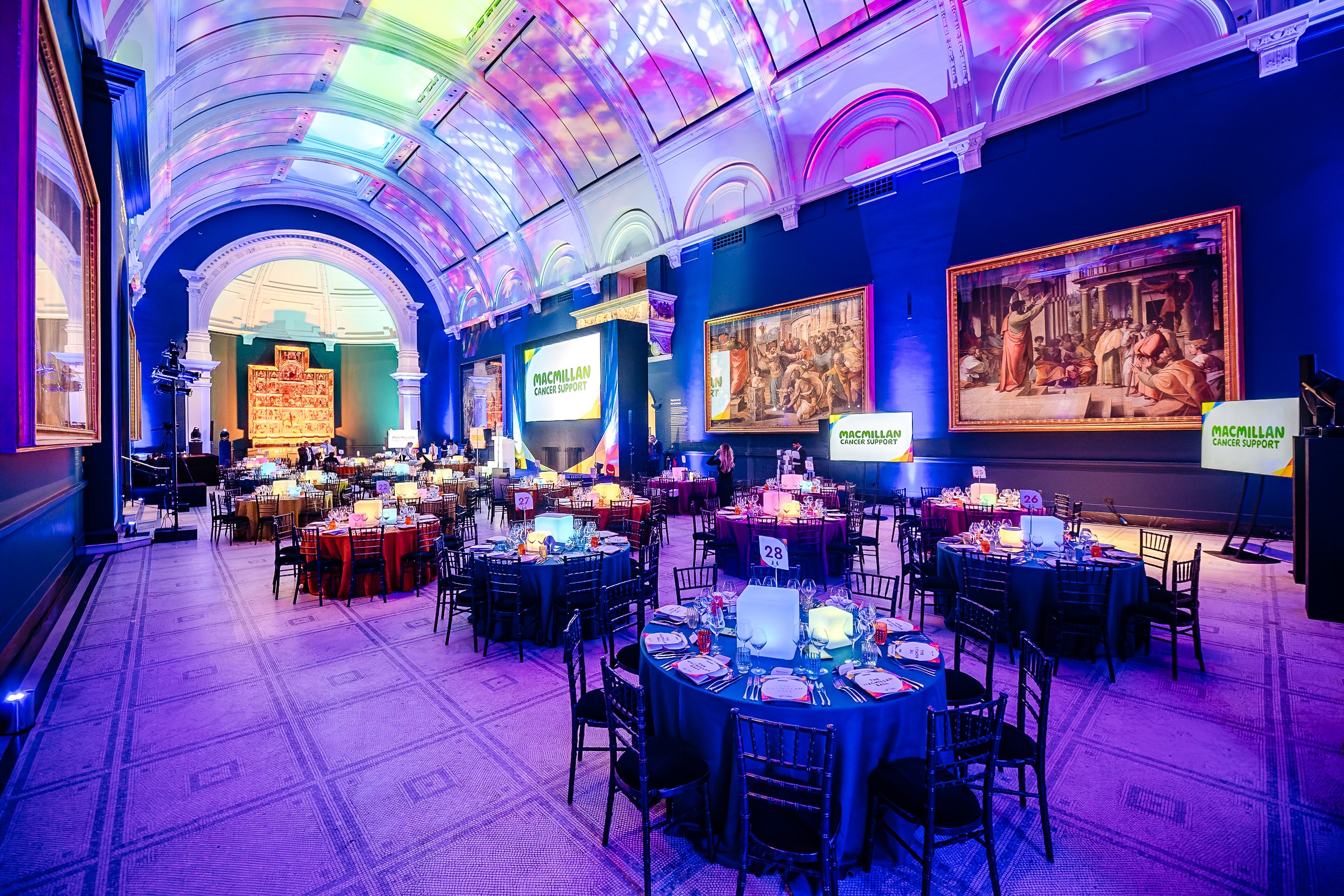 The grand gala dinner hall and luxury table setups for the Macmillan Cancer Support fundraiser at the Victoria and Albert Museum (V&A), London. Premium event venue photography by Will Bailey.