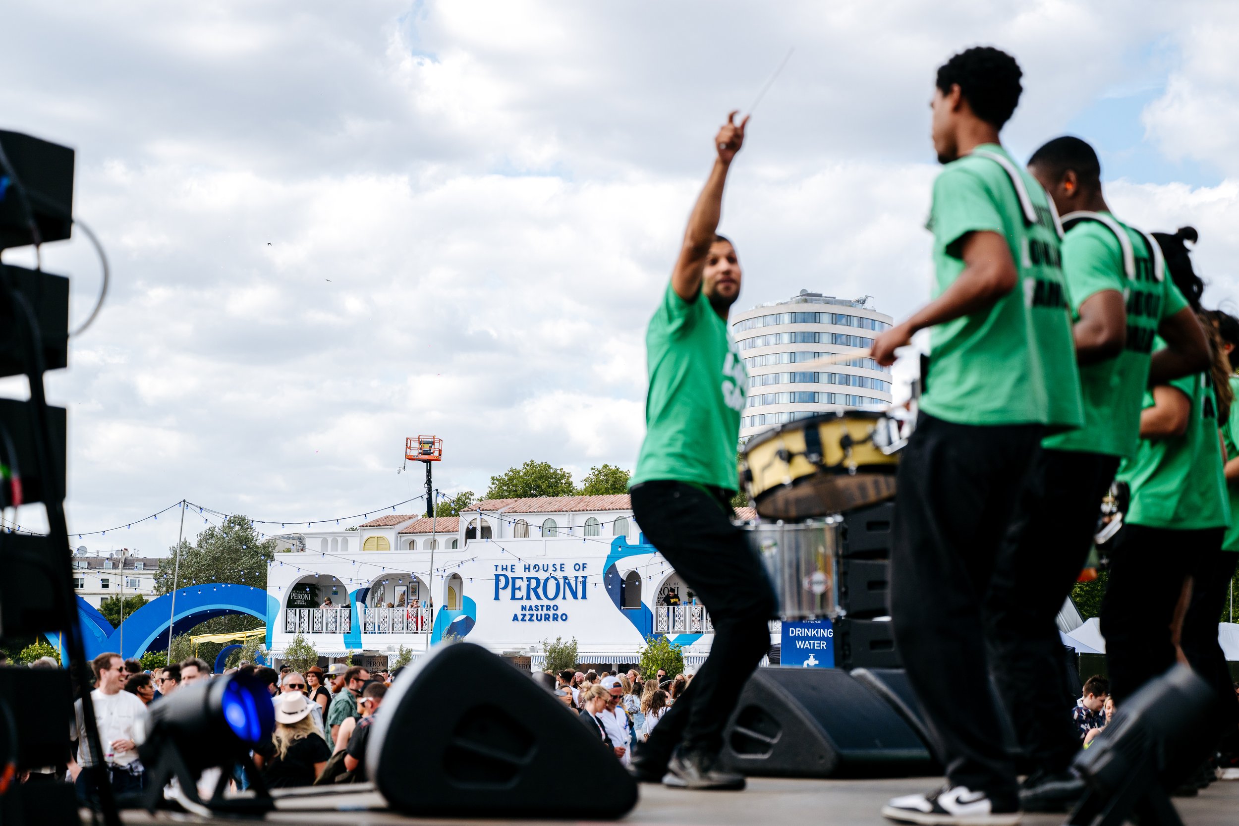 Live percussionists performing on stage to a crowd with the custom-built House of Peroni structure in the background at British Summer Time (BST) in Hyde Park, London. Dynamic music festival and event sponsor activation photography by Will Bailey.