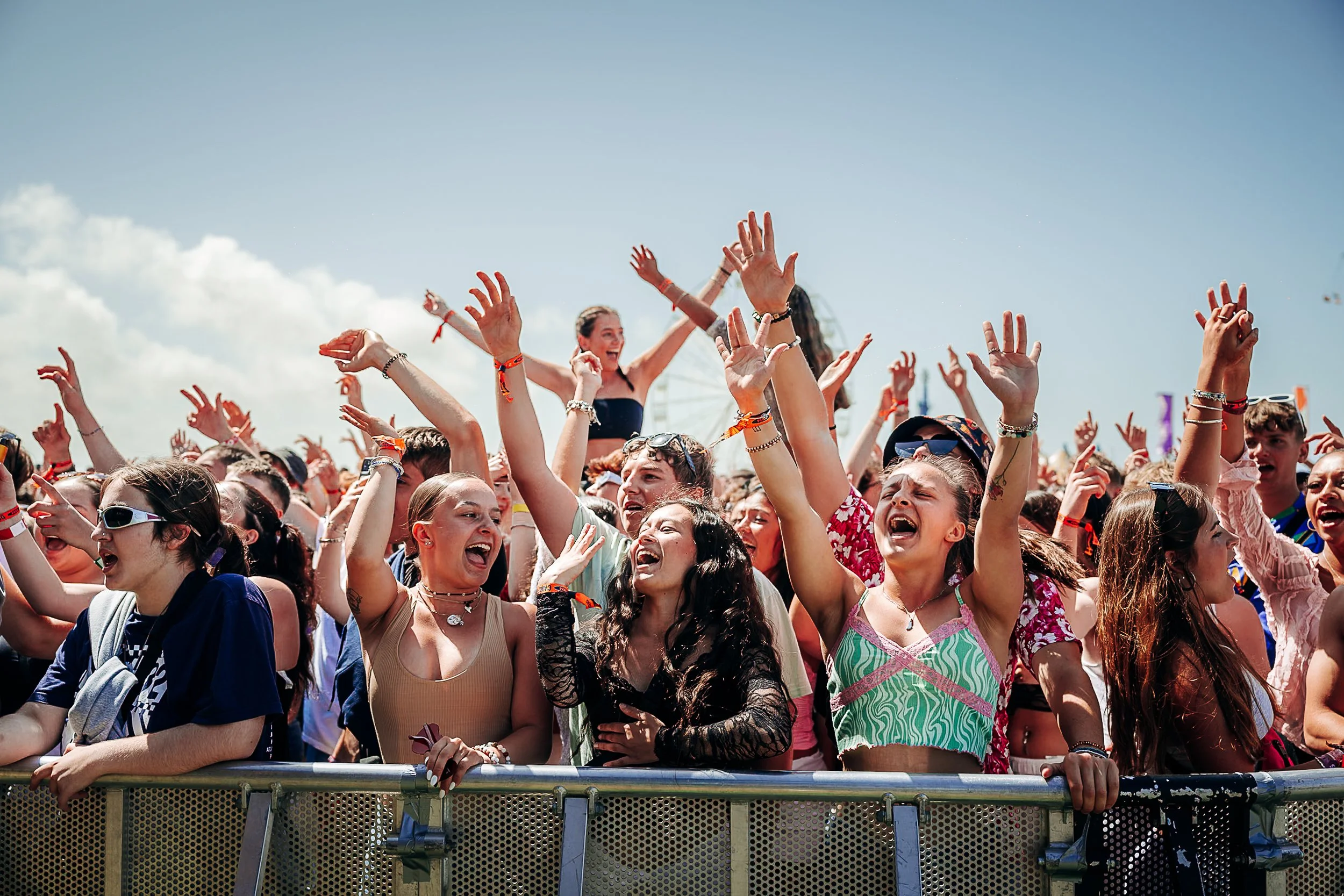 Daytime festival barrier photography capturing energetic attendees cheering and waving at the main stage during Boardmasters Festival in Cornwall, by Will Bailey.