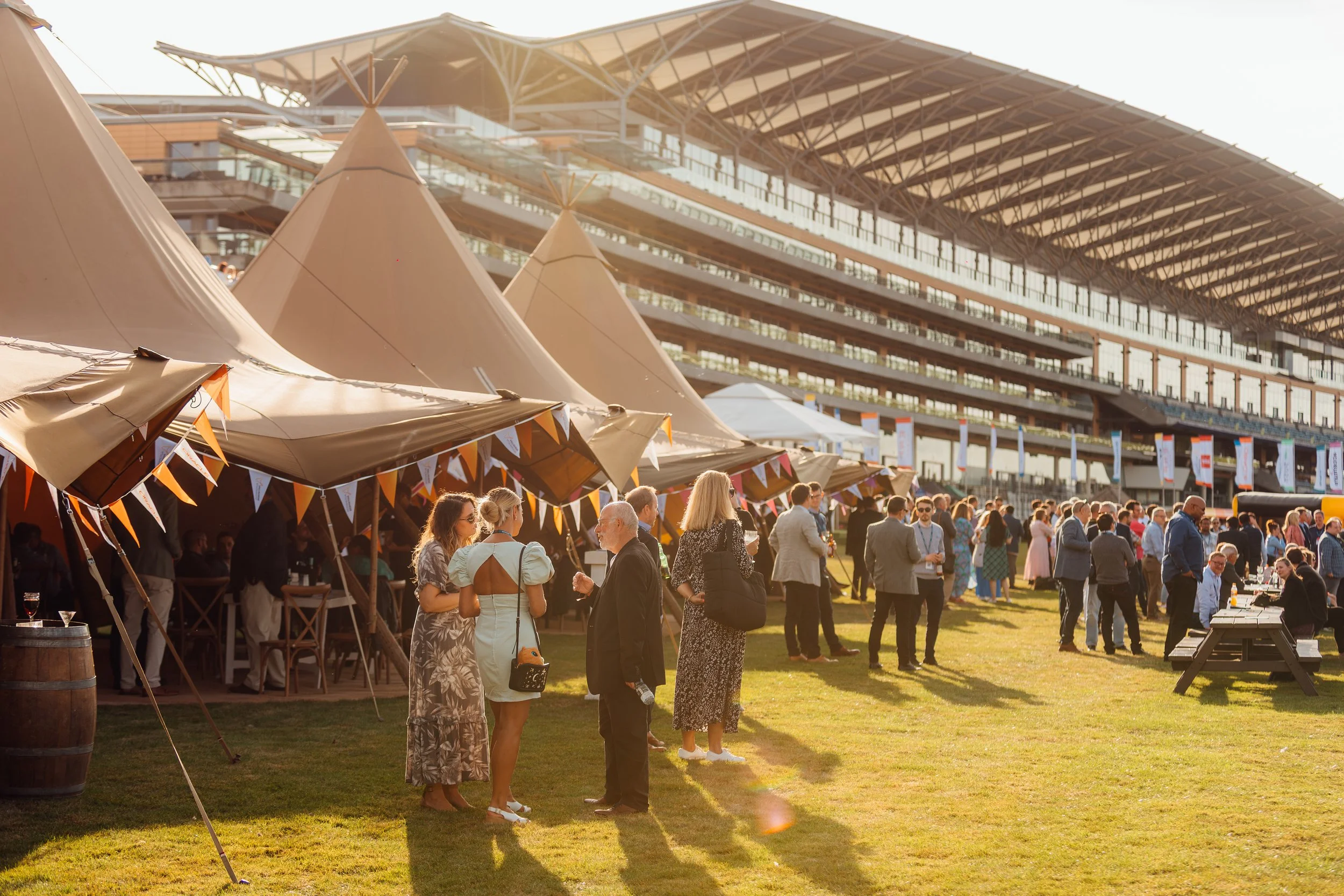 Guests mingling at the ERP Today awards and fundraiser outside the luxury tipi village at Ascot Racecourse. Golden hour corporate lifestyle photography by Will Bailey.
