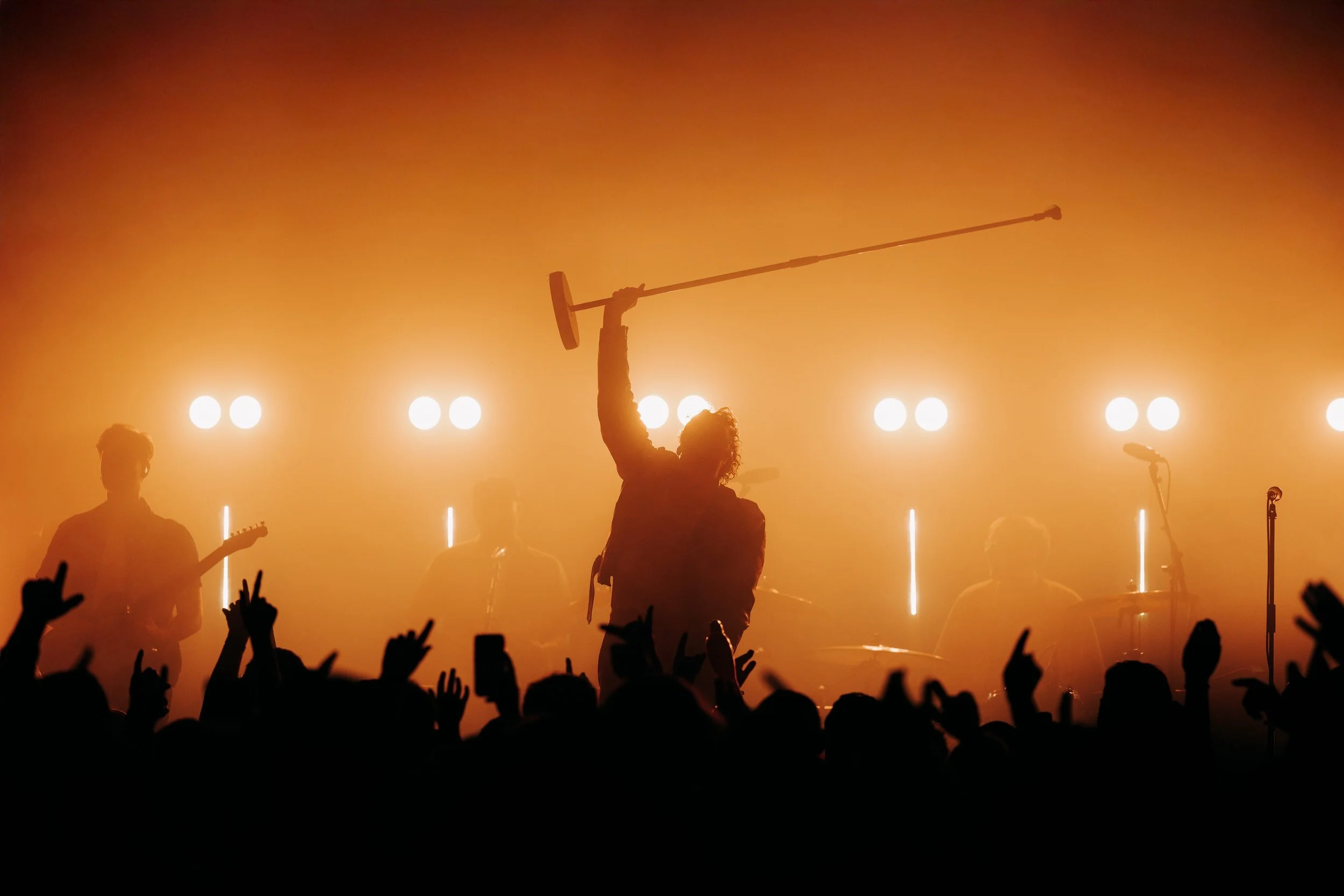 Live music photography of Kids In Glass Houses in Southampton, Hampshire. Silhouette of singer holding up a microphone stand on stage. Photo by Will Bailey.