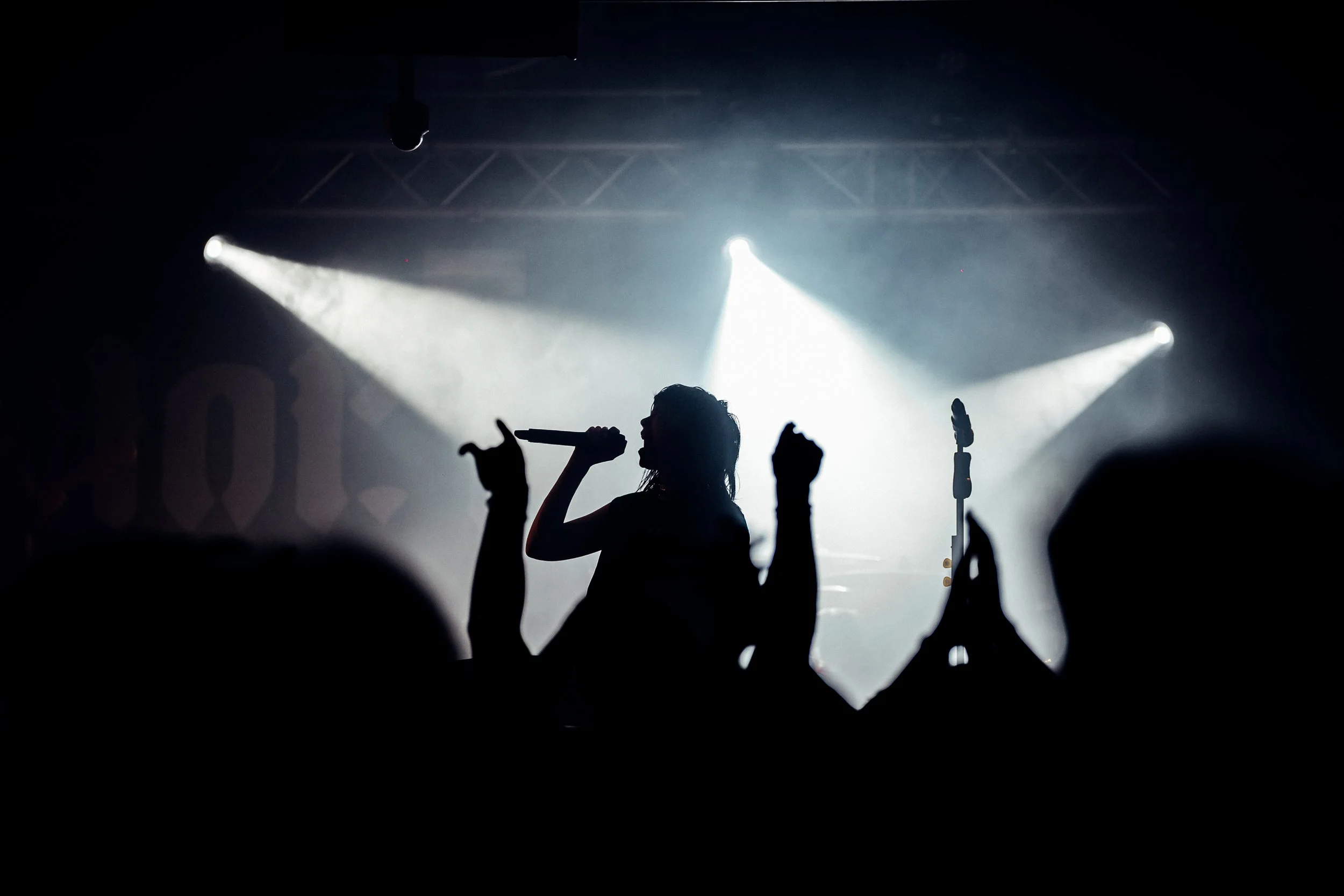 A striking silhouette of the lead singer of Hot Milk performing in front of blinding white spotlights at a leading live venue in Hampshire. Atmospheric alternative rock concert and creative venue stage lighting photography by Will Bailey.