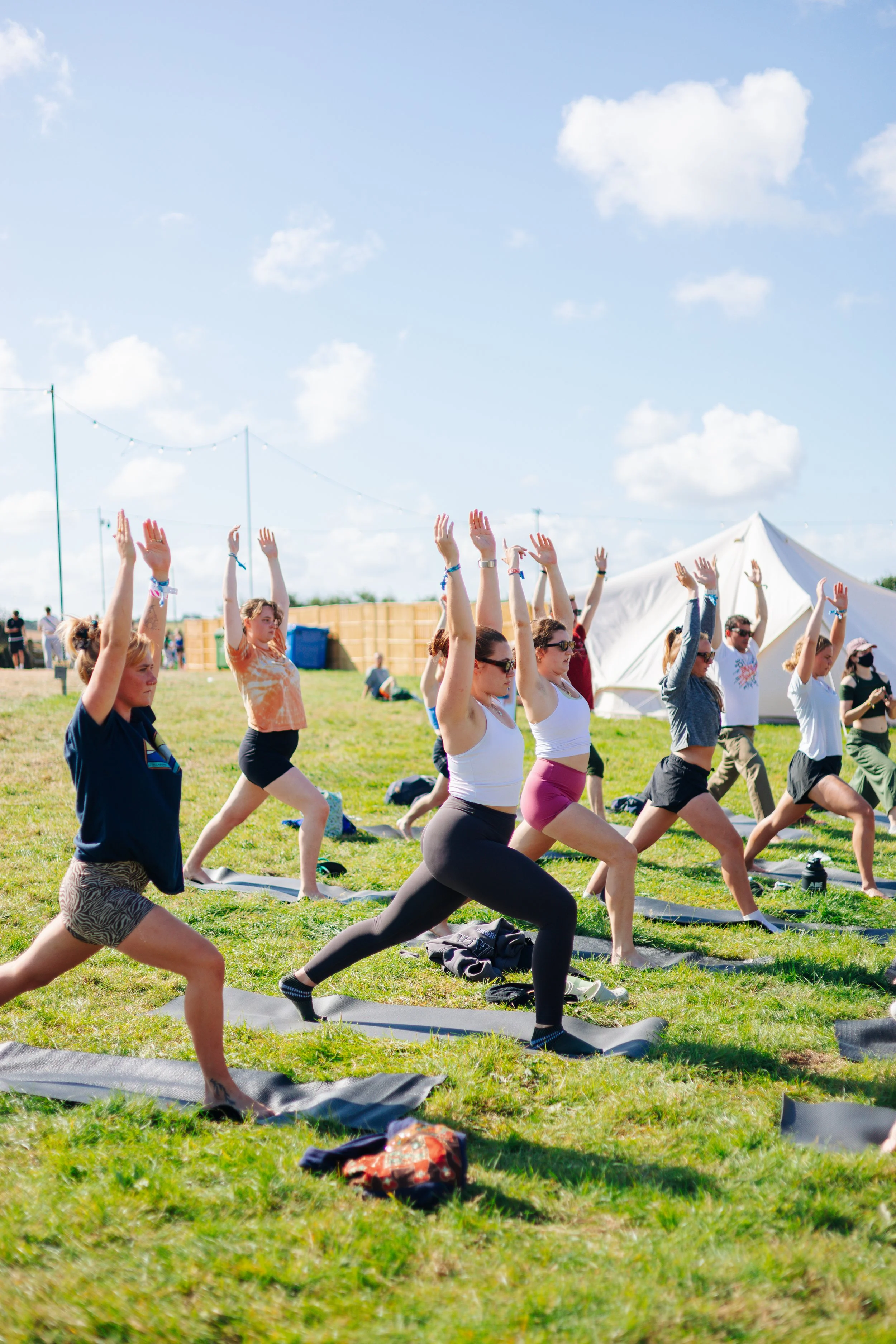 Festivalgoers participating in an organized morning yoga session at Zennor Haven during Boardmasters Festival in Cornwall. Coastal wellness programming and summer music festival lifestyle photography by Will Bailey.