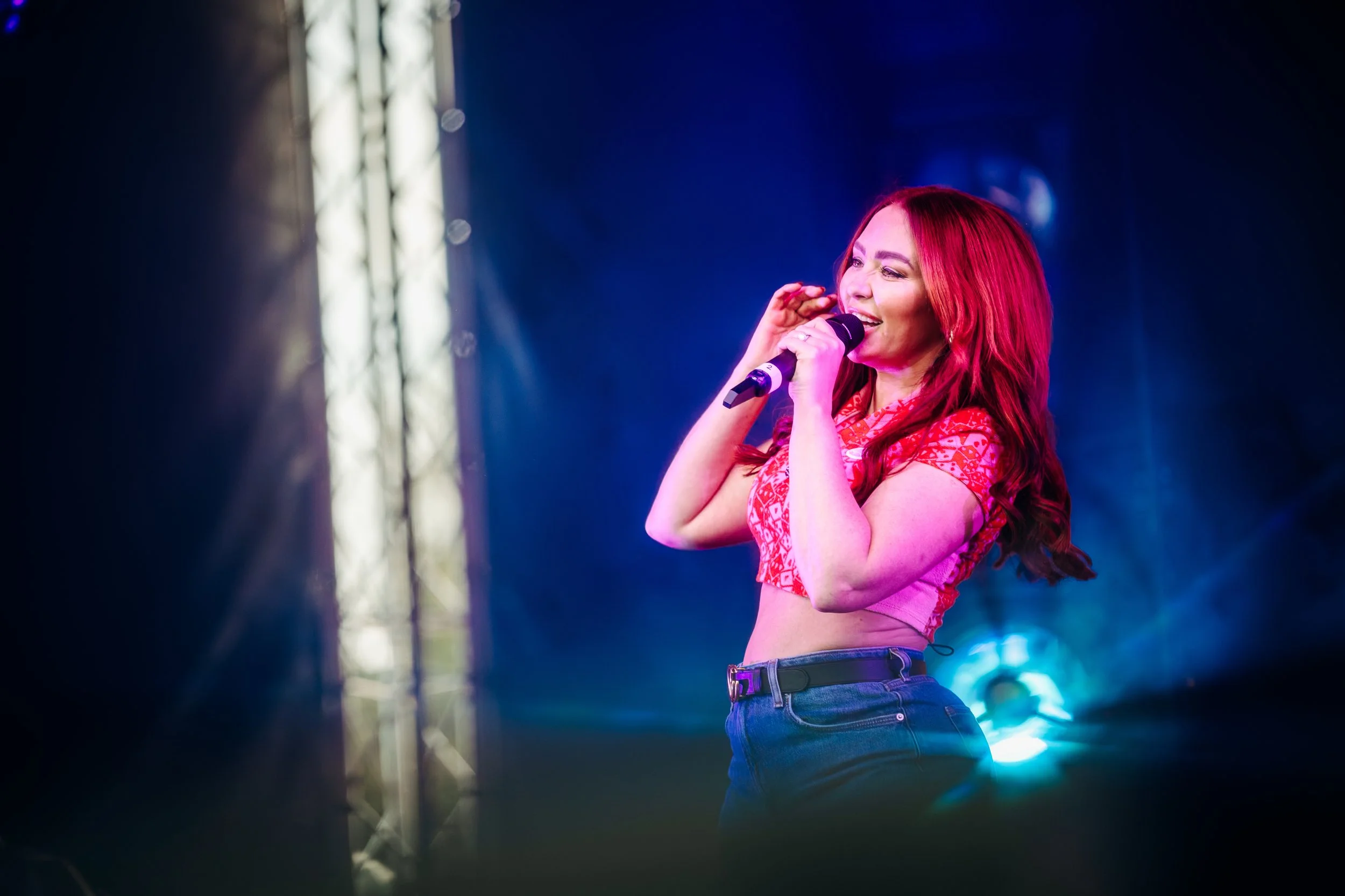 Pop group Atomic Kitten performing their classic hits live on stage beneath a blue spotlight at the Teddy Rocks Festival in Dorset. Professional charity music festival and high-profile pop concert photography by Will Bailey.