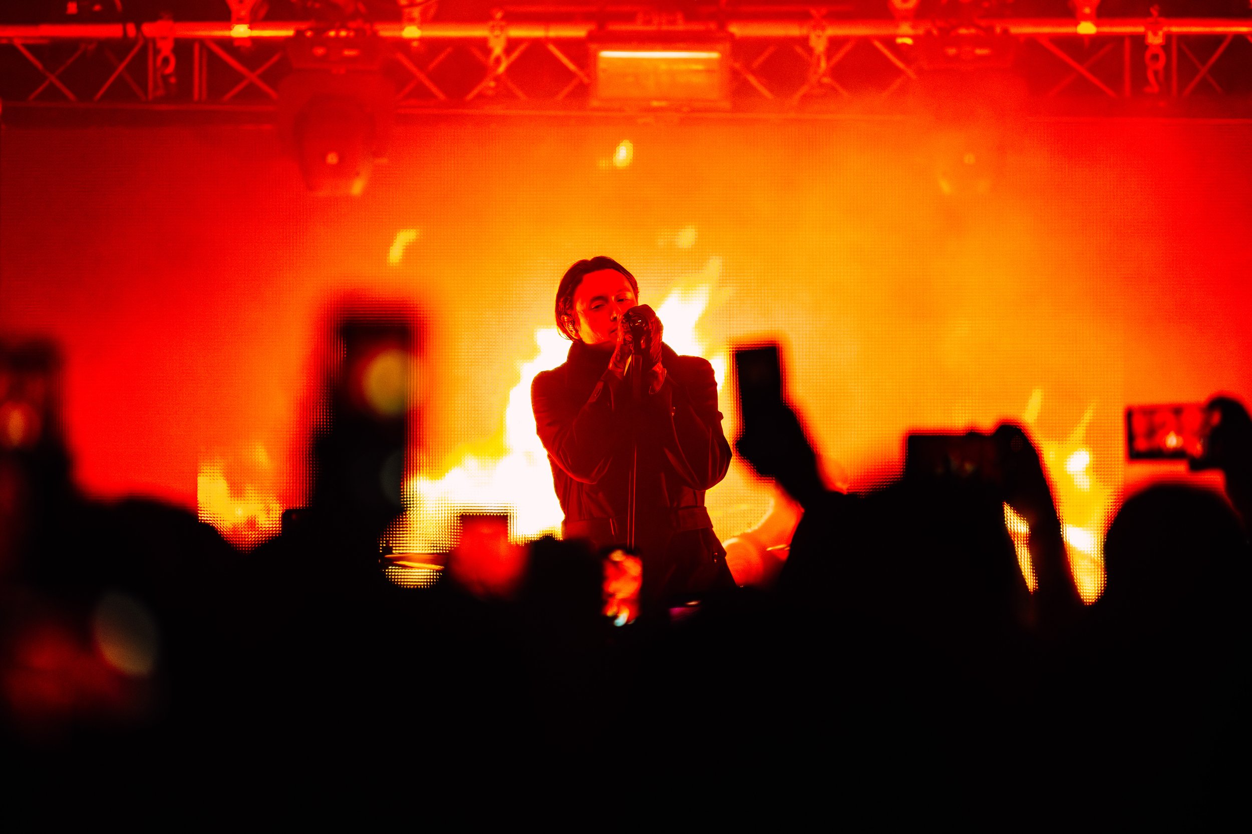 The lead vocalist of metalcore band Bad Omens performing live against a backdrop of dramatic digital flame graphics at a popular independent concert venue in Southampton. Intense rock concert and atmospheric venue stage lighting photography by Will B