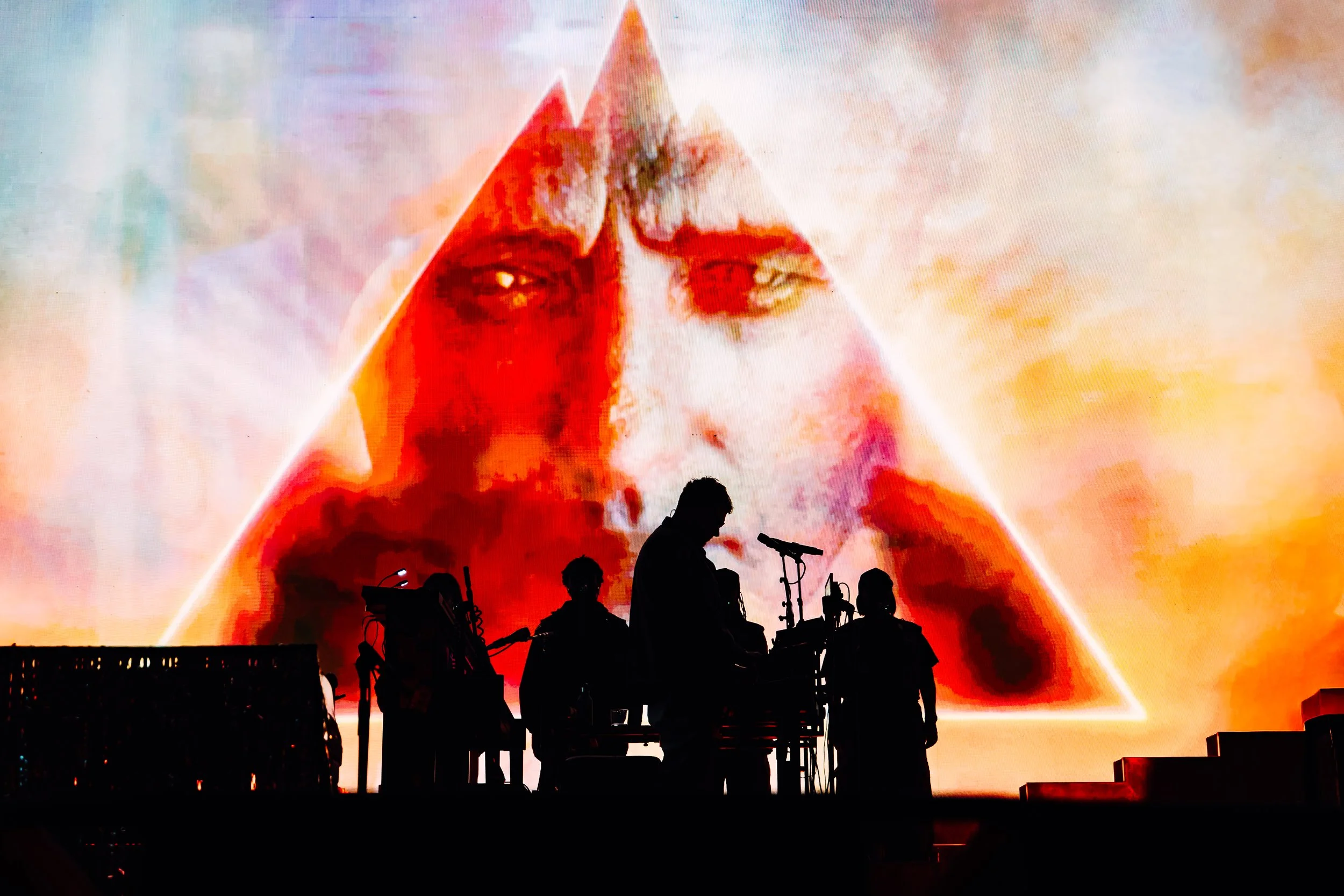 A silhouette profile of the live touring band members of Gorillaz performing in front of an illuminated screen at the Cardiff International Arena. Creative concert lighting silhouettes and stadium-level production photography by Will Bailey.