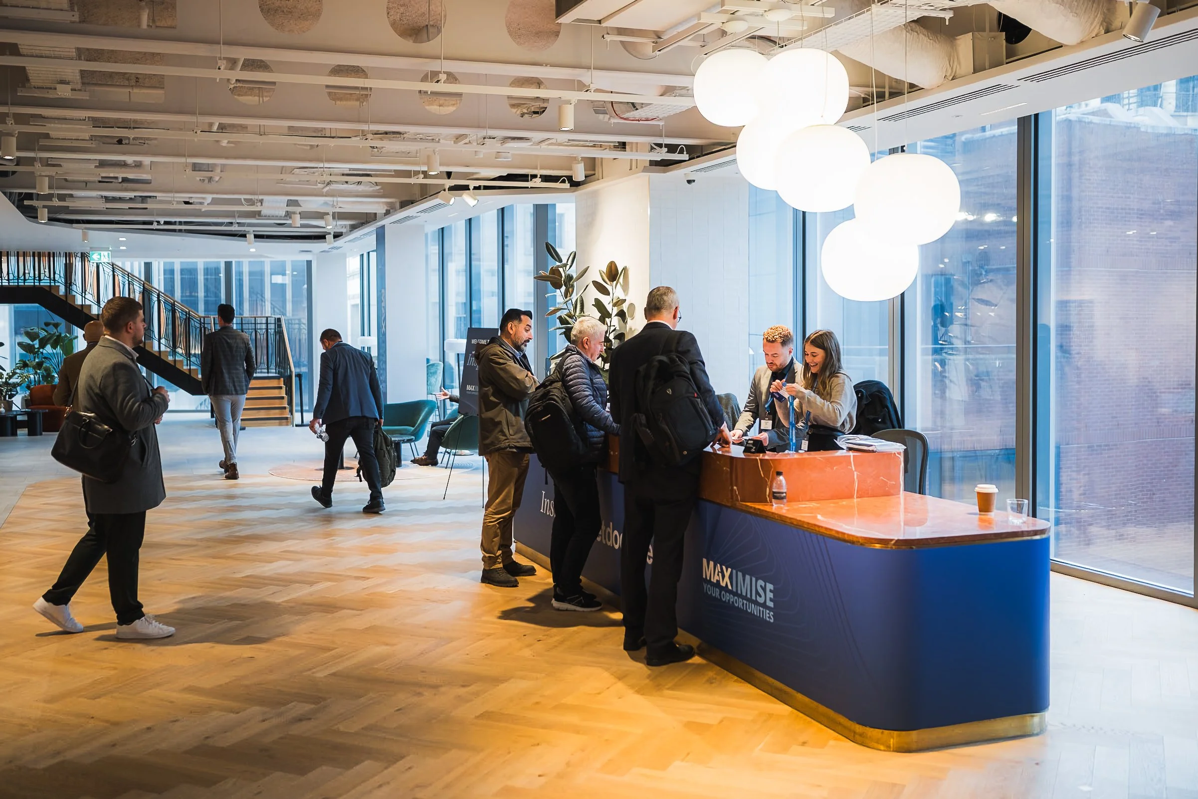 Attendees checking in and collecting lanyards at the registration desk inside Convene 22 Bishopsgate for the NetDocuments Inspire conference, London. Corporate event logistics and summit photography by Will Bailey.