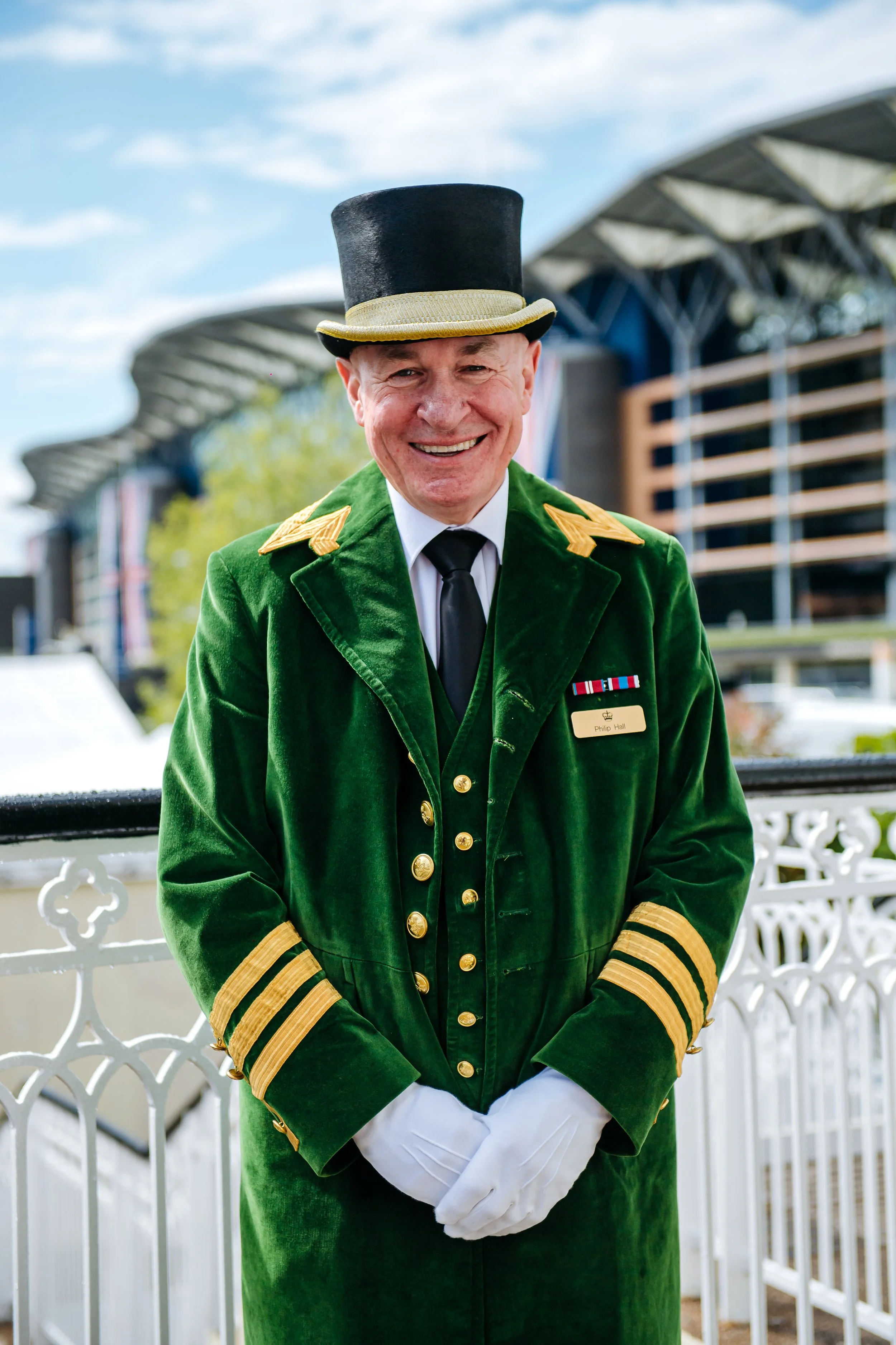 A formal portrait of an iconic Ascot Greencoat official in traditional velvet livery on the balcony terraces at Ascot, Berkshire. Premium corporate heritage and luxury sporting season lifestyle photography by Will Bailey.