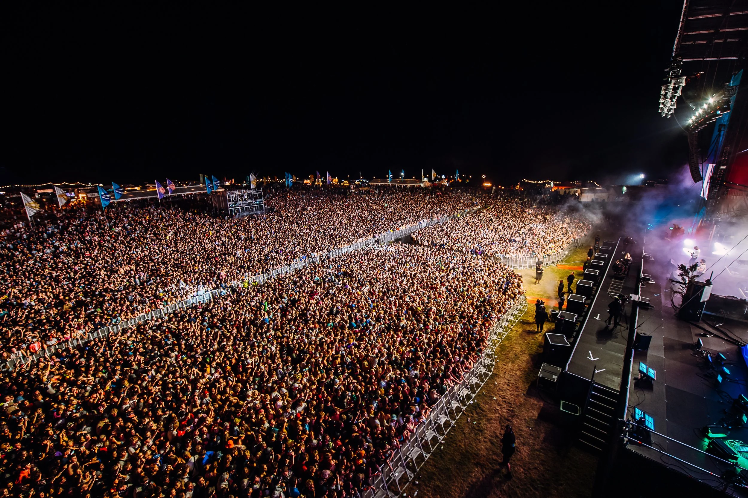 High-angle night-time main stage photography showcasing a massive crowd of thousands at Boardmasters Festival during a headline performance by Foals, shot by Will Bailey.