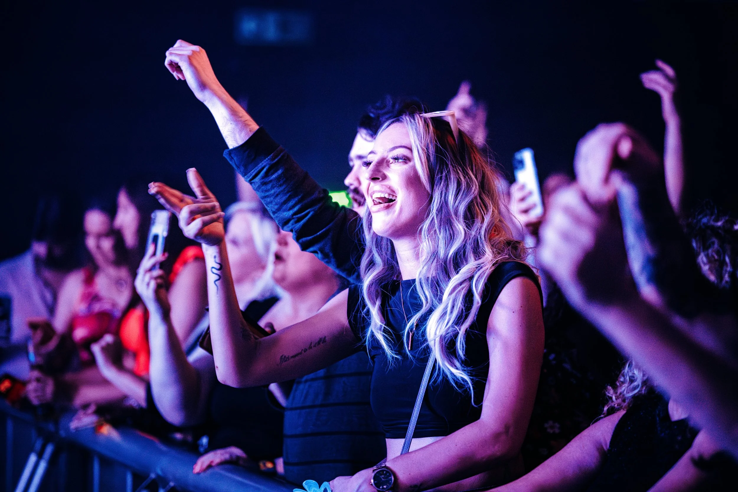An excited crowd of music fans singing along at the front barrier during an energetic live gig at an independent concert venue in Southampton, Hampshire. Candid audience atmosphere and music fan culture photography by Will Bailey.
