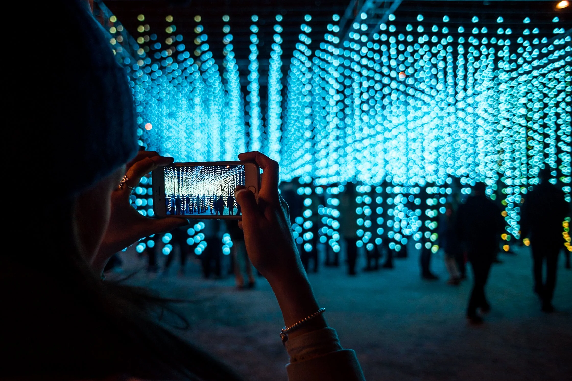 An attendee uses a smartphone to capture a perspective frame of the immersive, glowing installation path at the Southampton Festival of Light. Creative nighttime public art and light festival photography by Will Bailey.