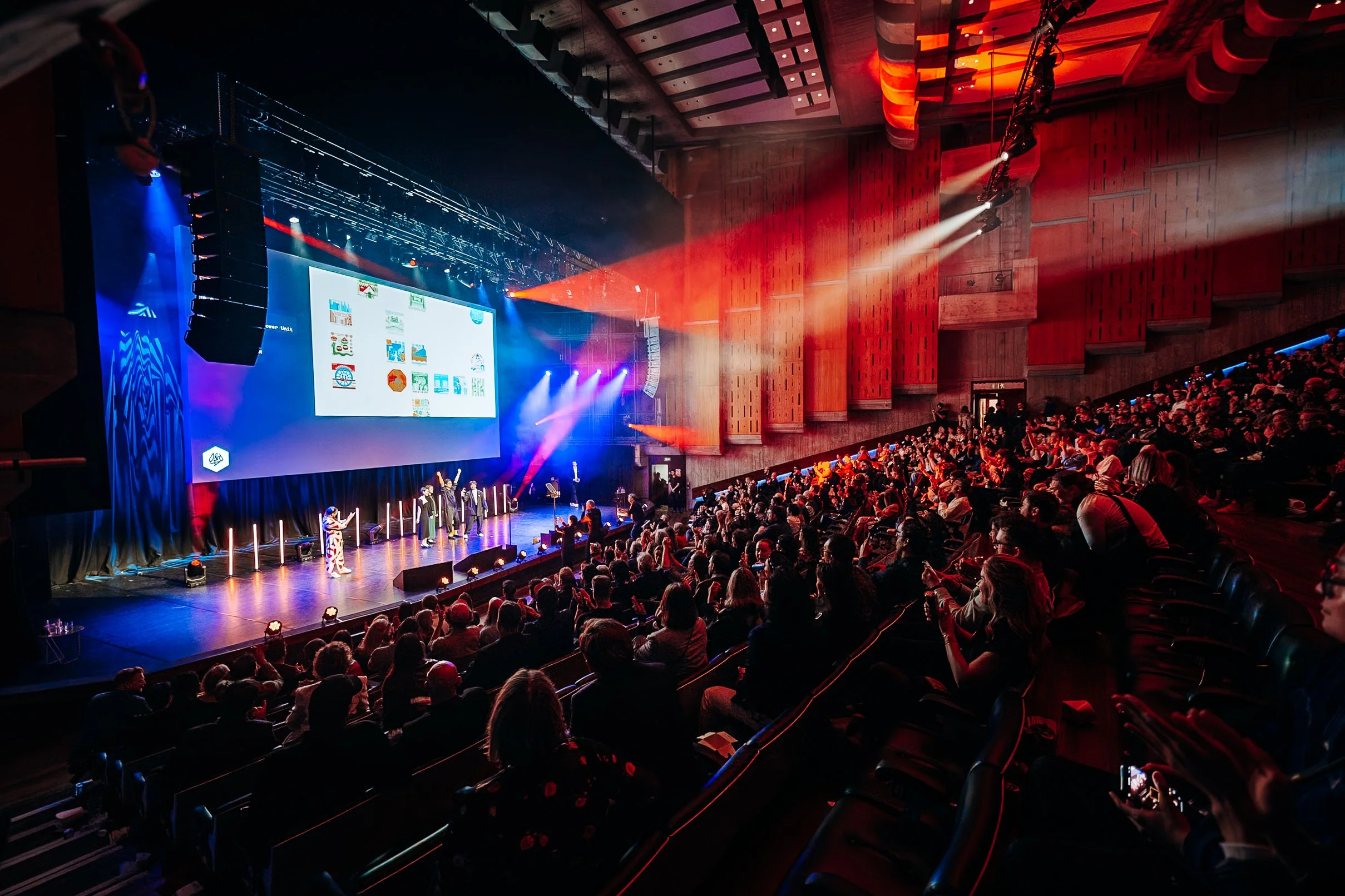 A wide high-angle perspective of the massive auditorium audience and live stage presentation during the D&AD Awards at the Southbank Centre, London. Premium creative industry awards and large-scale event photography by Will Bailey.