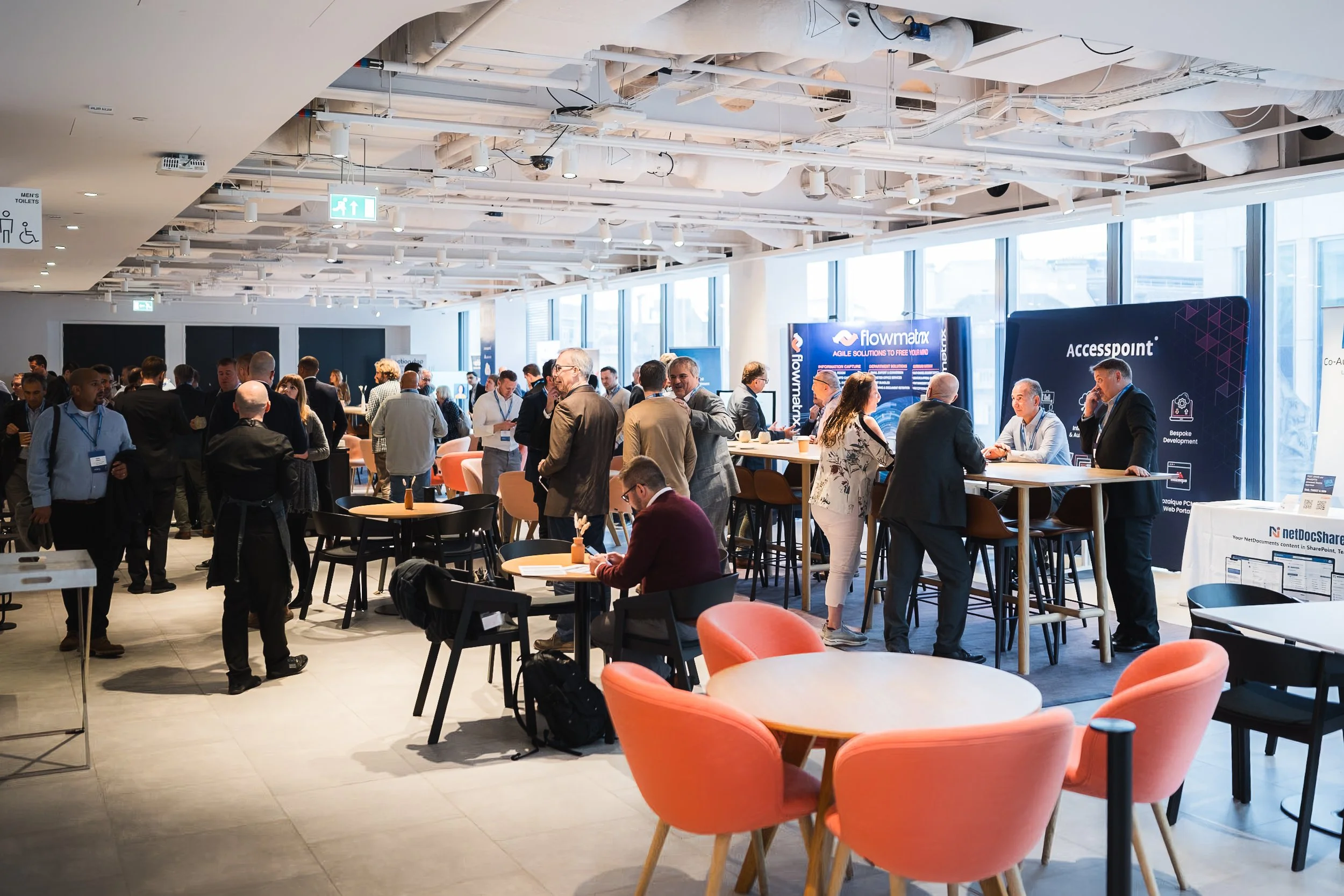 Attendees and sponsors networking in the exhibition breakout hall at the NetDocuments Inspire conference, Convene 22 Bishopsgate, London. Corporate event and summit photography by Will Bailey.