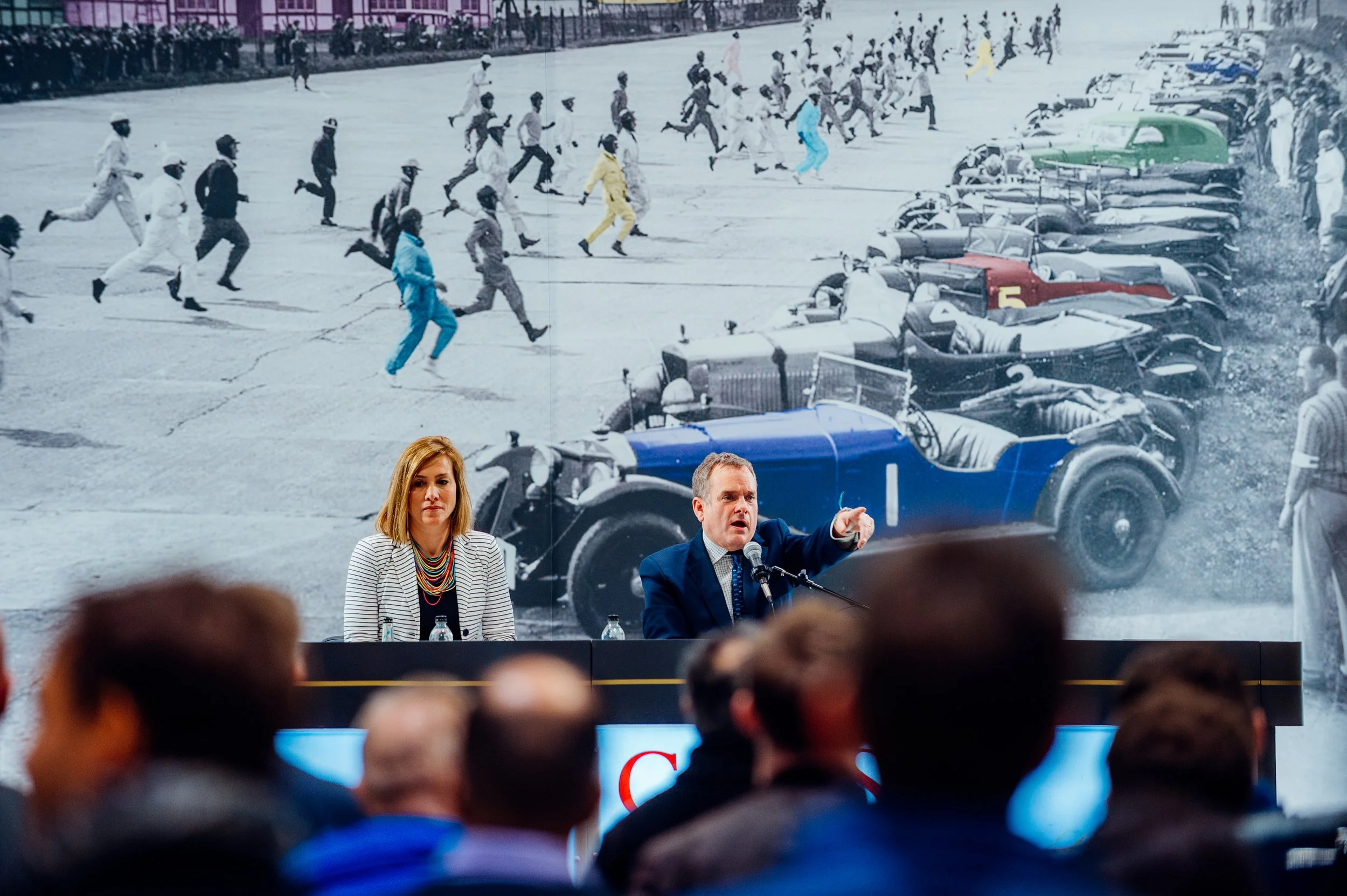 Auctioneers conducting a live bidding session on stage in front of collectors during a prestigious COYS classic car auction in London. Luxury automotive auction and collector event photography by Will Bailey.