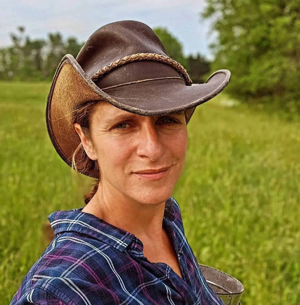Founder of Nourishing Circles Farmstead standing in a Nova Scotia field wearing a cowboy hat and plaid shirt.