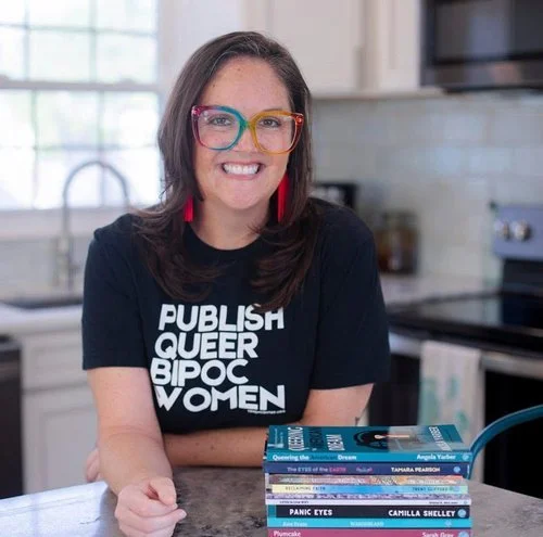 Rev. Dr. Angela Yarber, founder of Tehom Center Publishing, wearing a Publish Queer BIPOC Women t-shirt and holding books