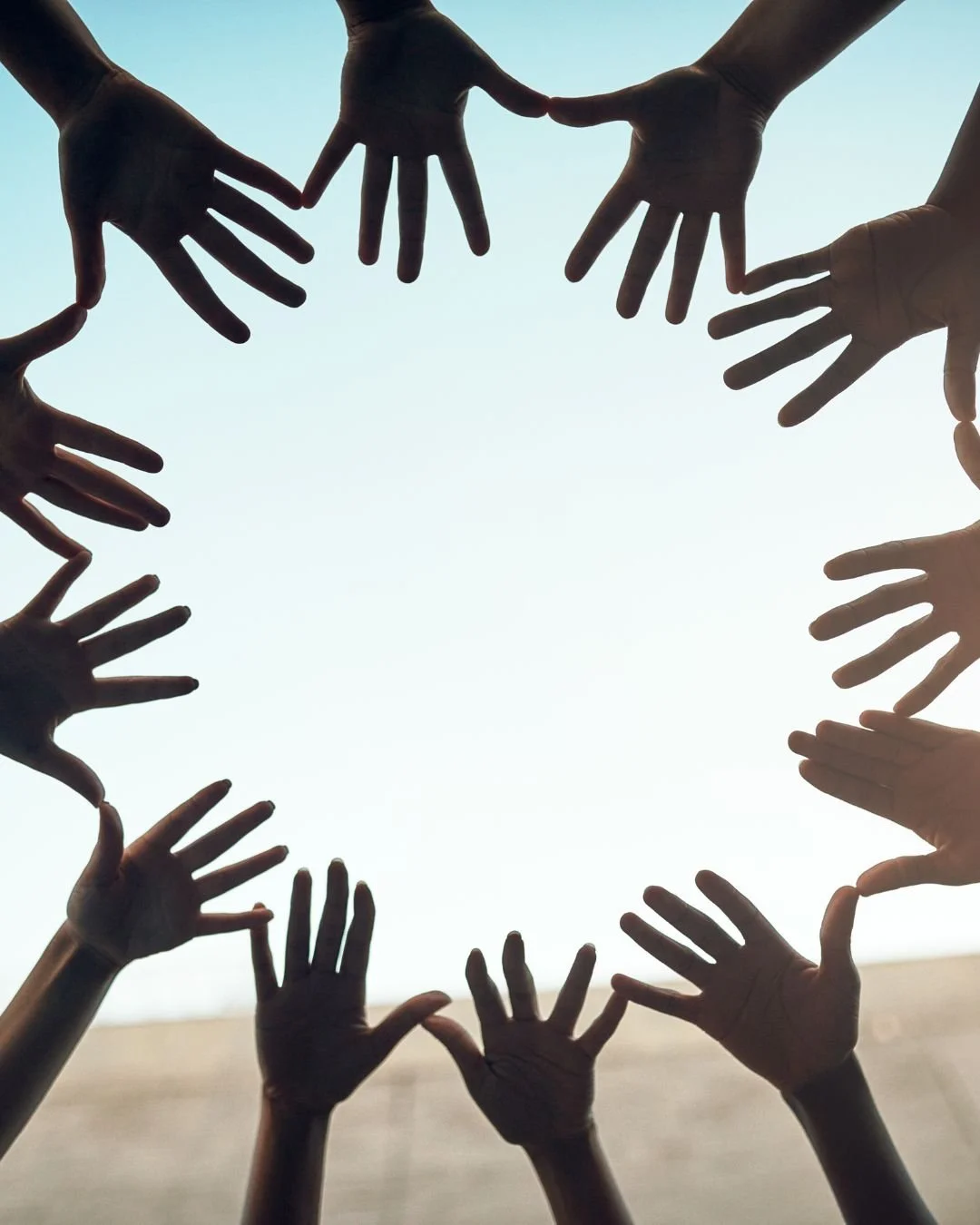 Multiple hands reaching towards the sky forming a circle.