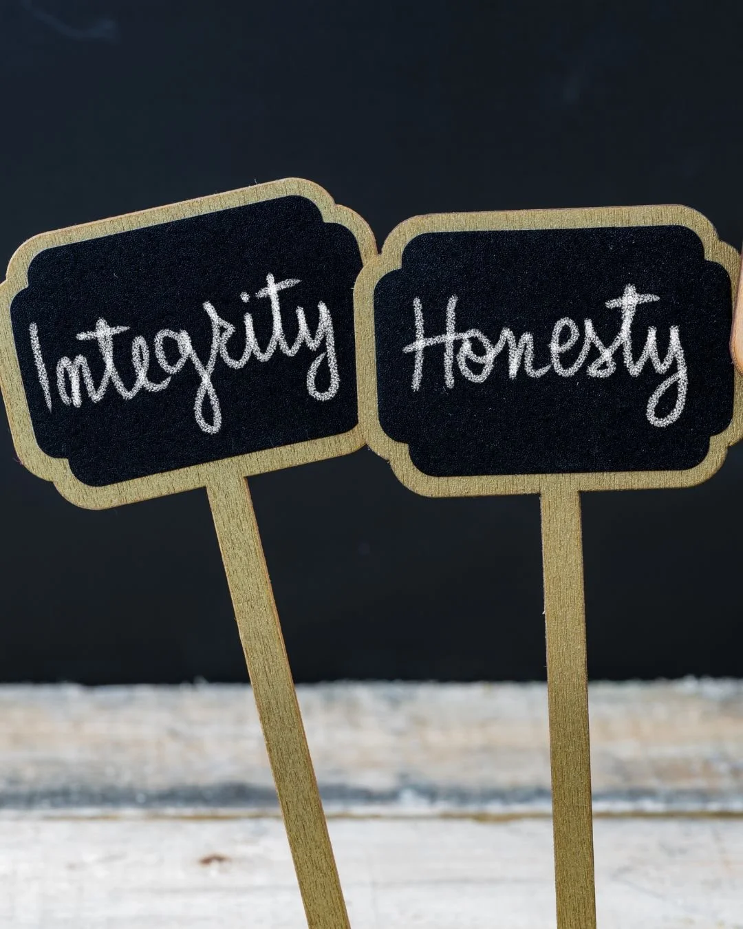 Two small chalkboard signs with wooden sticks, one says 'Integrity' and the other 'Honesty' in white handwritten letters.