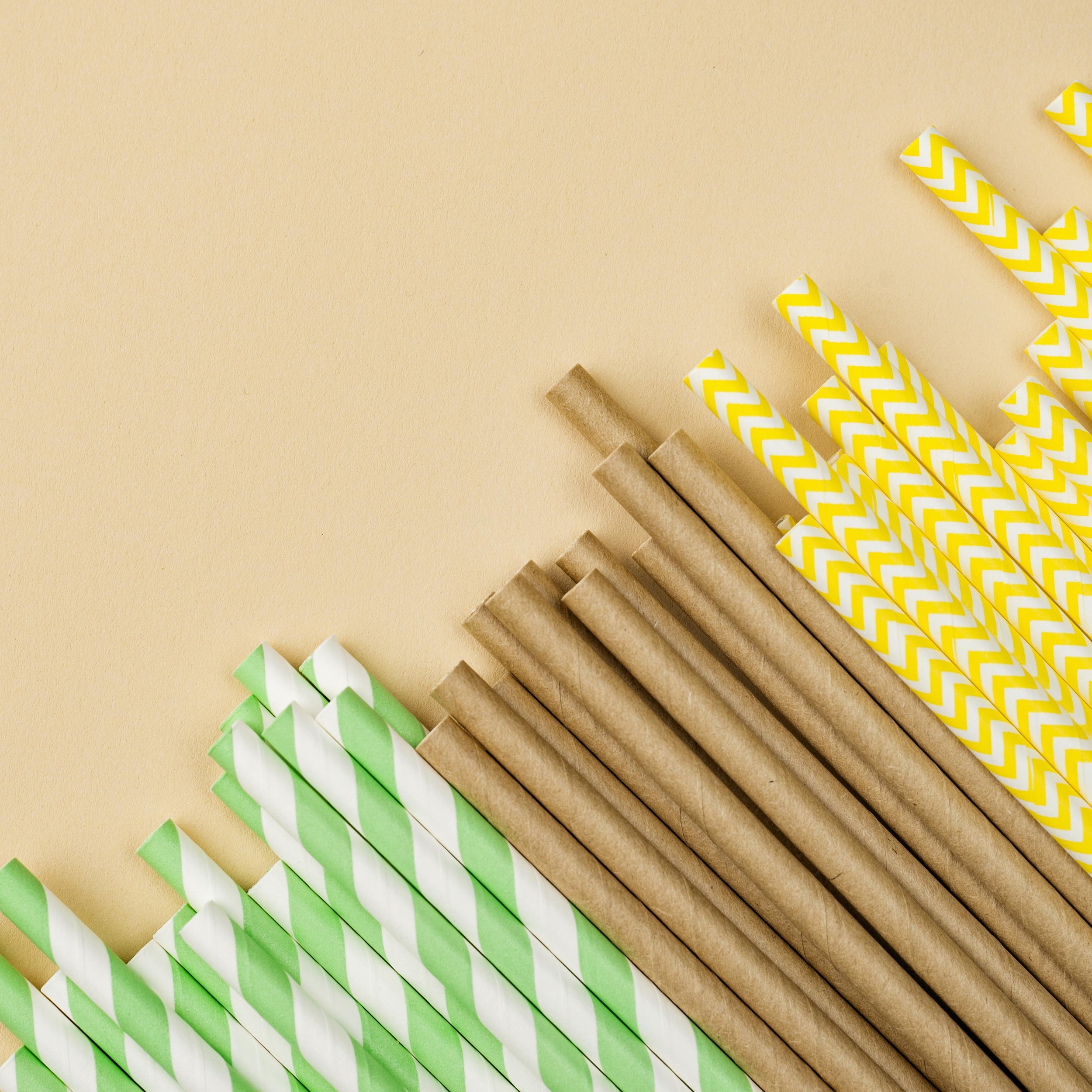 Colorful striped paper straws arranged on a beige background.