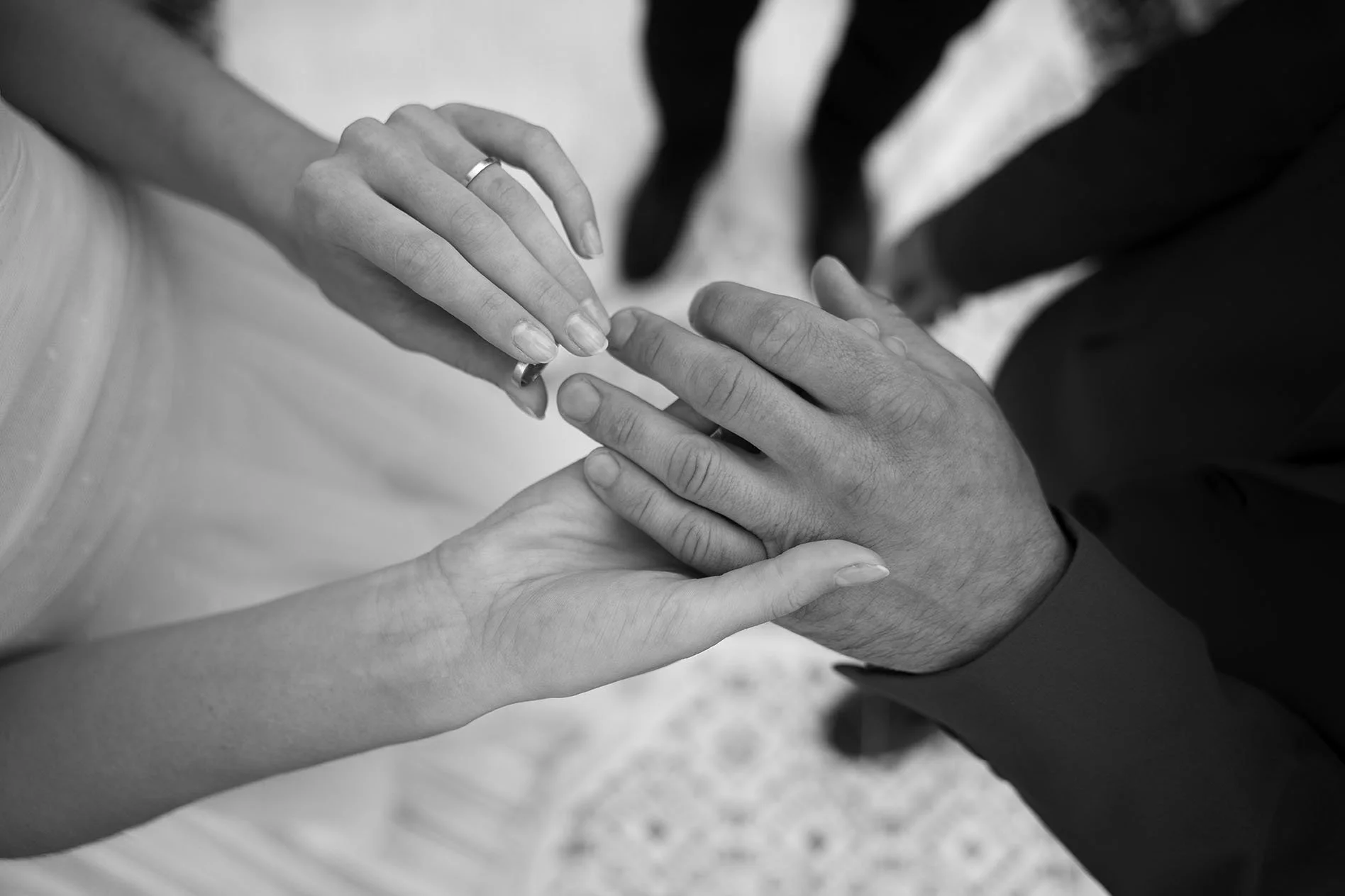 Close-up of two hands, one with wedding ring, holding the other person's hand in a gesture of connection.