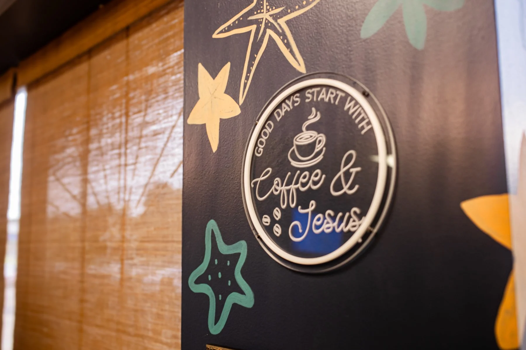 Decorative sign with a coffee cup illustration and the words 'Good days start with coffee & Jesus,' surrounded by starfish and starfish-like shapes on a dark background.