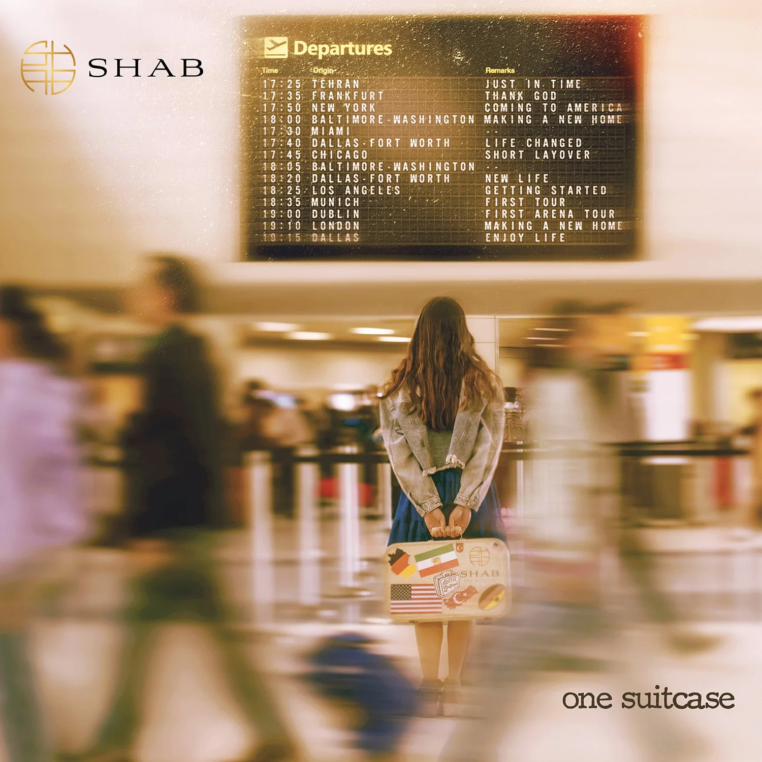 SHAB standing at an airport baggage claim area with a small suitcase decorated with flags. She is facing away from the camera, looking at the departure board. The words "one suitcase" appear at the bottom right of the image.