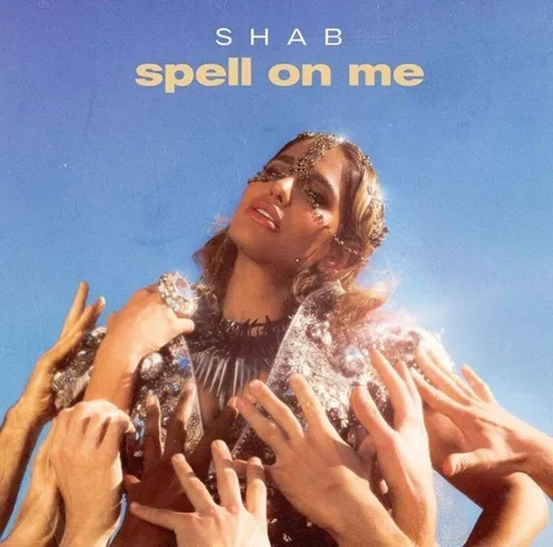 Album cover for Shab's "Spell on Me," featuring a woman with shiny makeup and glitter on her face, surrounded by multiple hands reaching toward her against a clear blue sky background.
