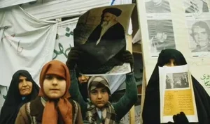 Women and children holding a large portrait of a man at a gathering or protest.