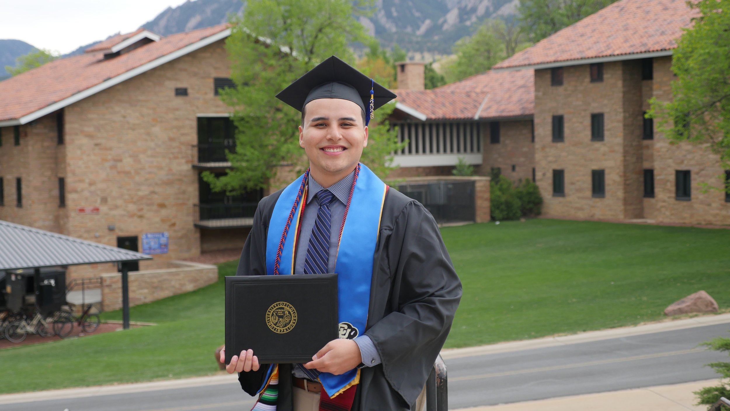 Isidro Elizondo Estrada holding his diploma after graduating from the Personal Financial Planning program at CU Boulder