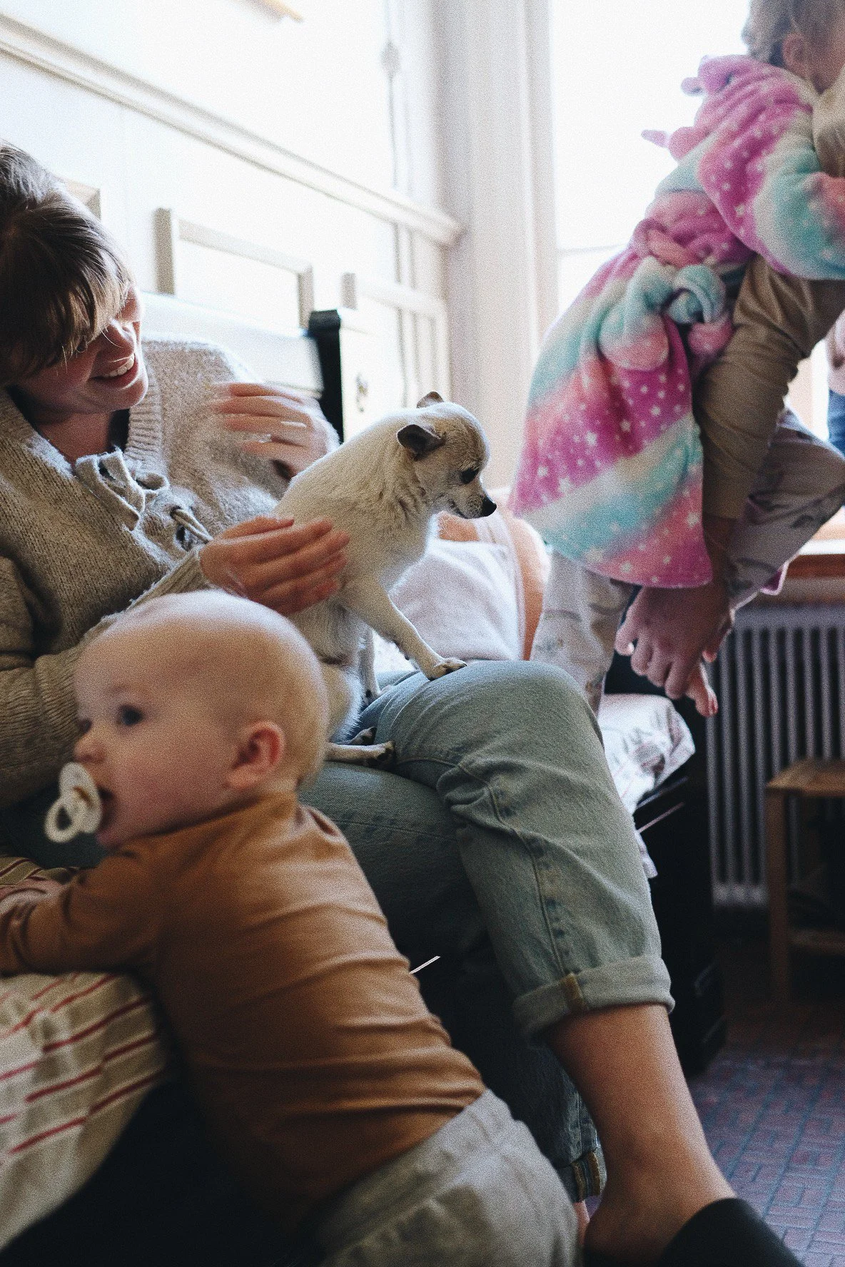 Två vuxna och två barn som sitter i ett vardagsrum, samt en liten hund.