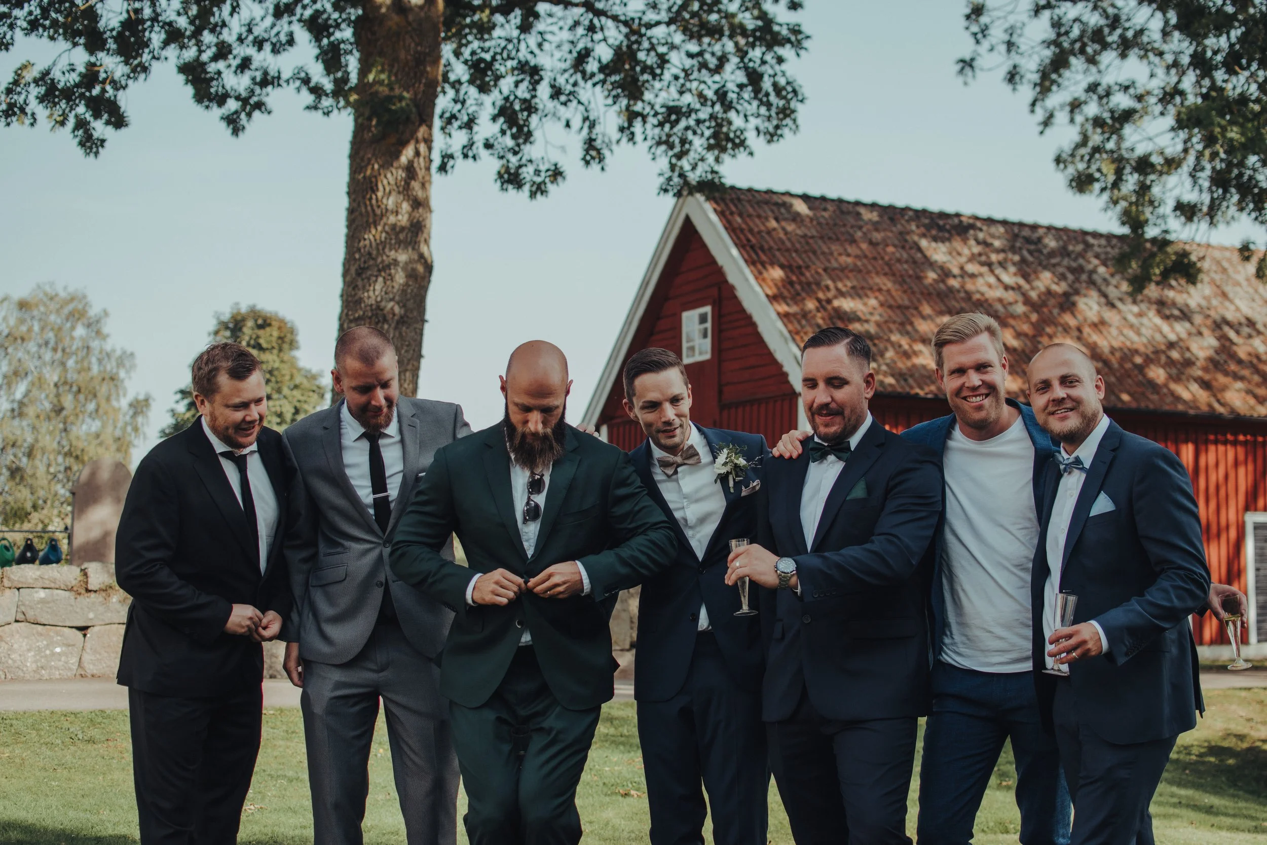 Grupp av män i formella kläder som står tillsammans utomhus, ler och pratar.