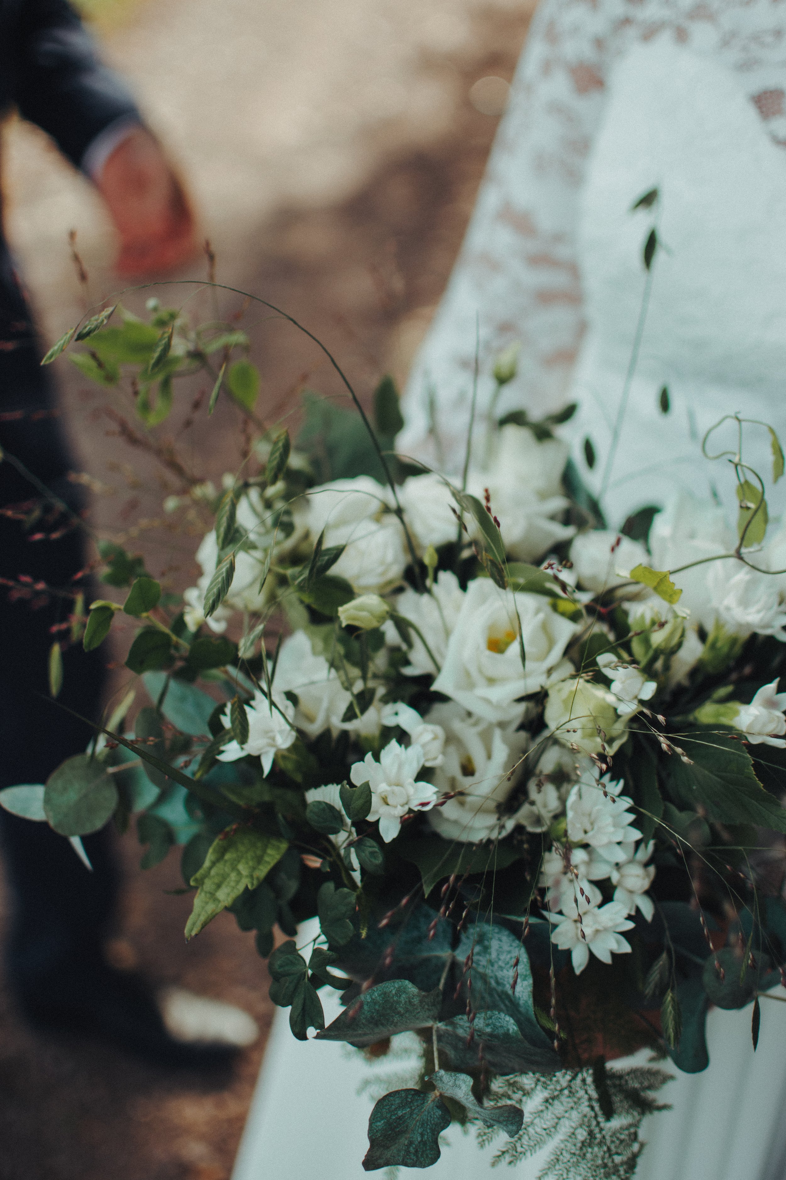 En brudbukett med vita blommor och gröna blad.