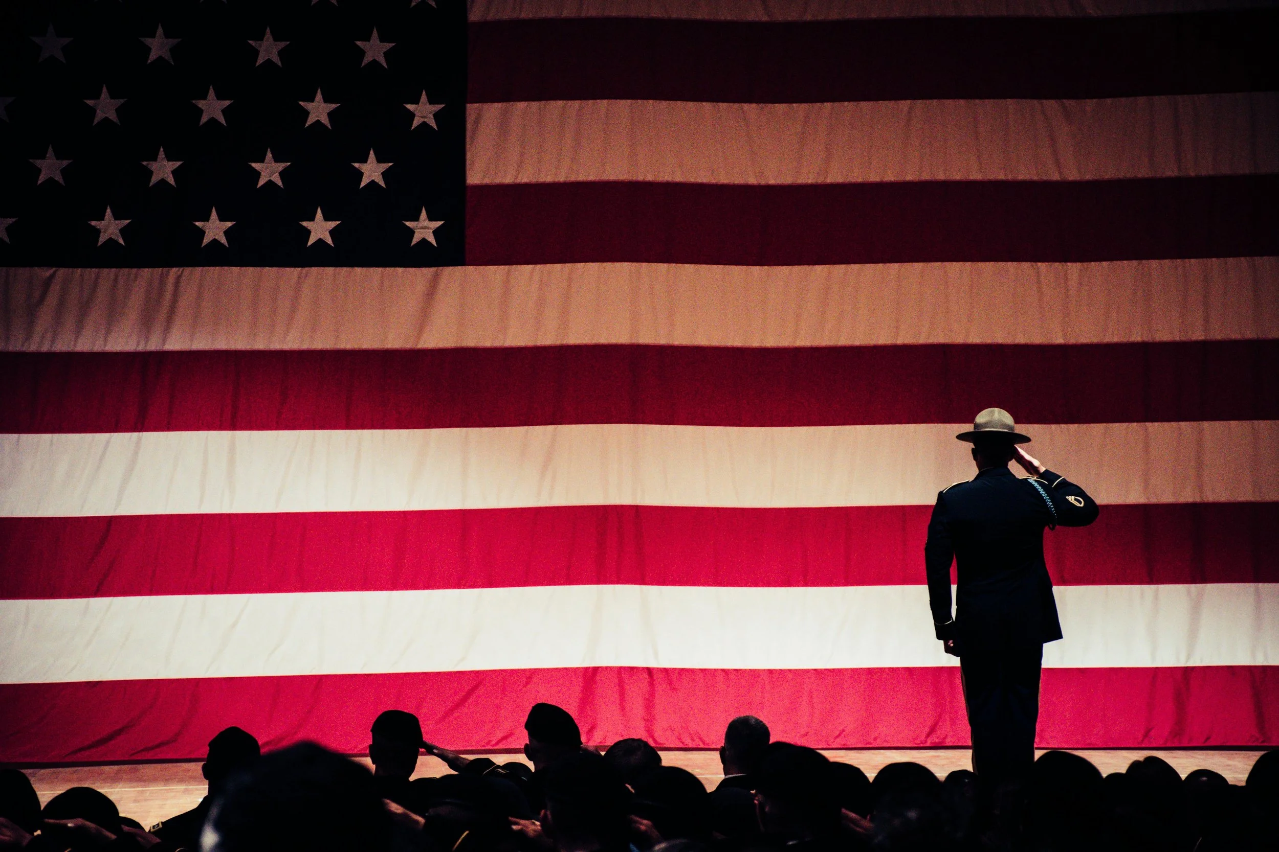 A powerful moment while US Veterans is saluting the US flag on stage during a presentation.