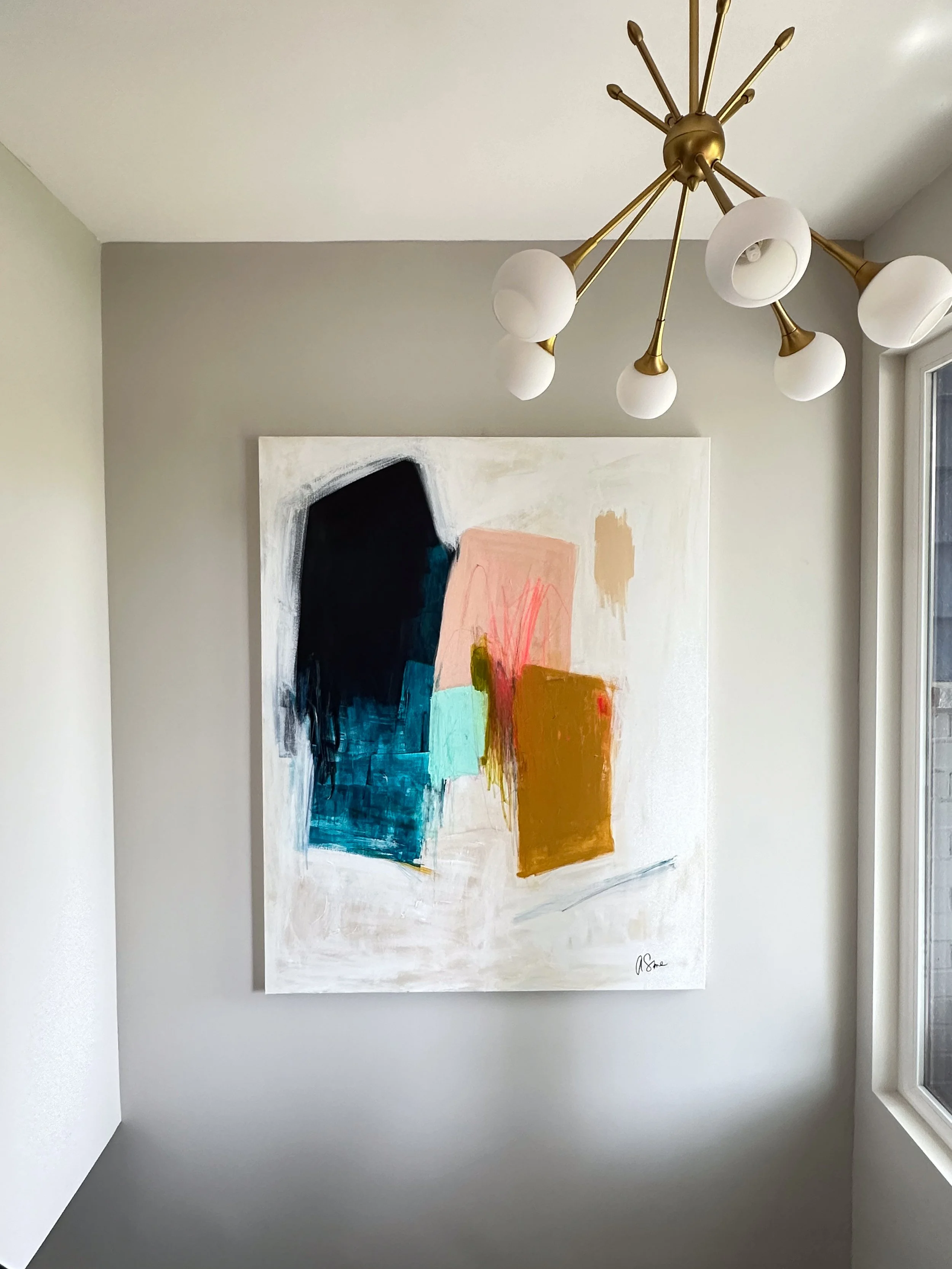 An abstract painting featuring geometric shapes in colors such as black, teal, pink, beige, and orange on a white canvas. The painting is signed by the artist in the bottom right corner.