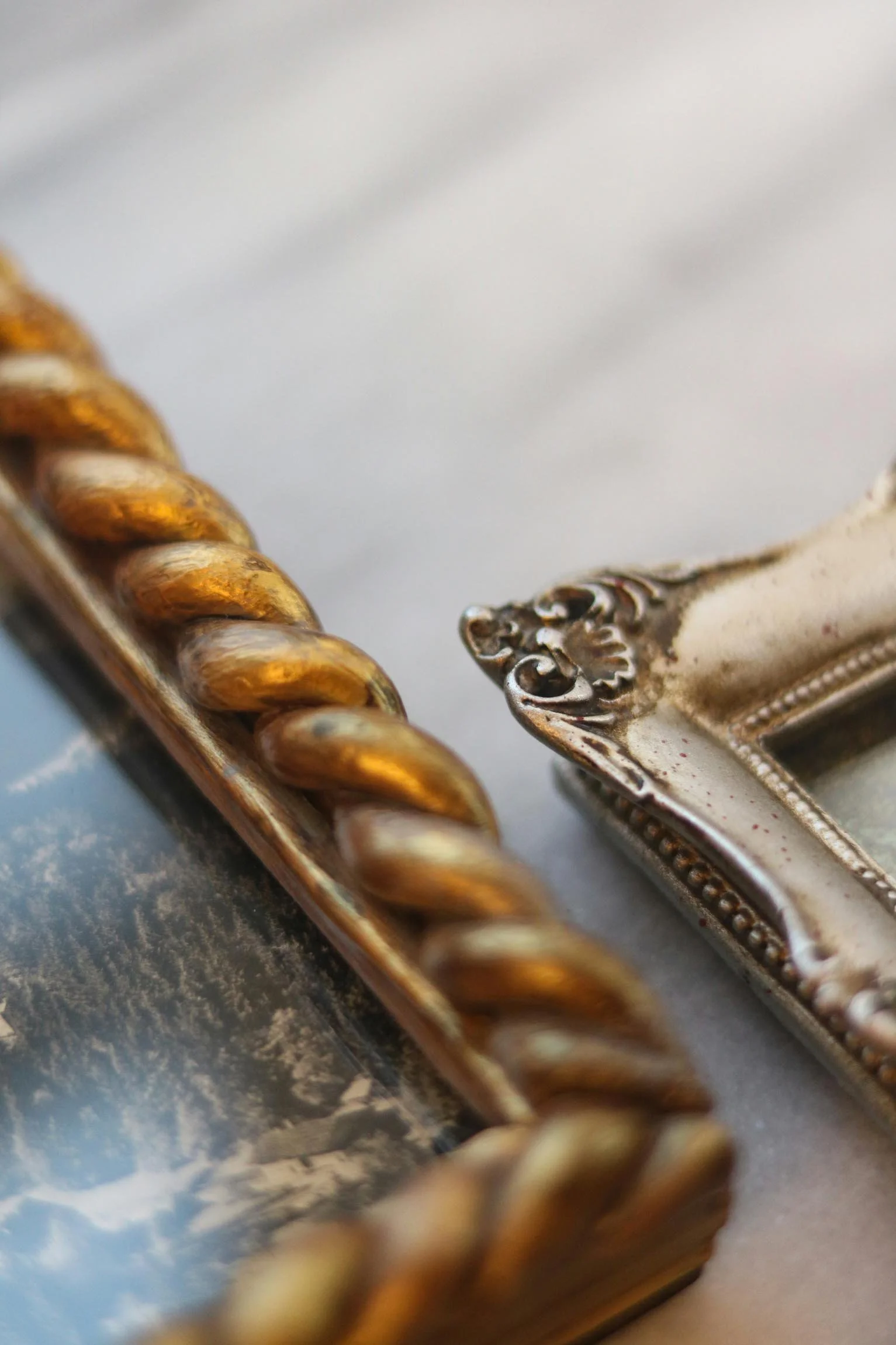 Close-up of a decorative silver dish with ornate edge and a gold twisted rope border, against a background of fluffy clouds and blue sky.