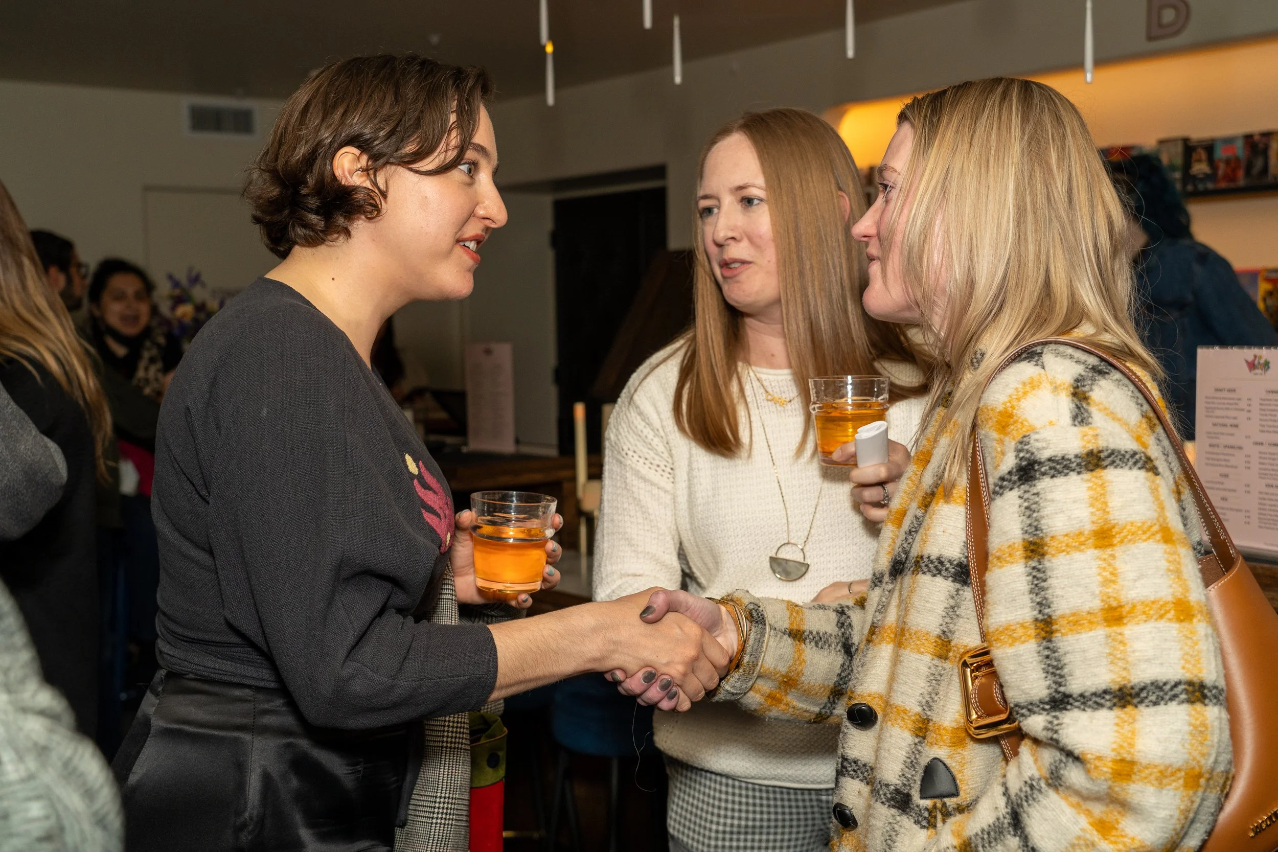  Three women networking and shaking hands at the Familiar Touch special preview screening in Los Angeles. 