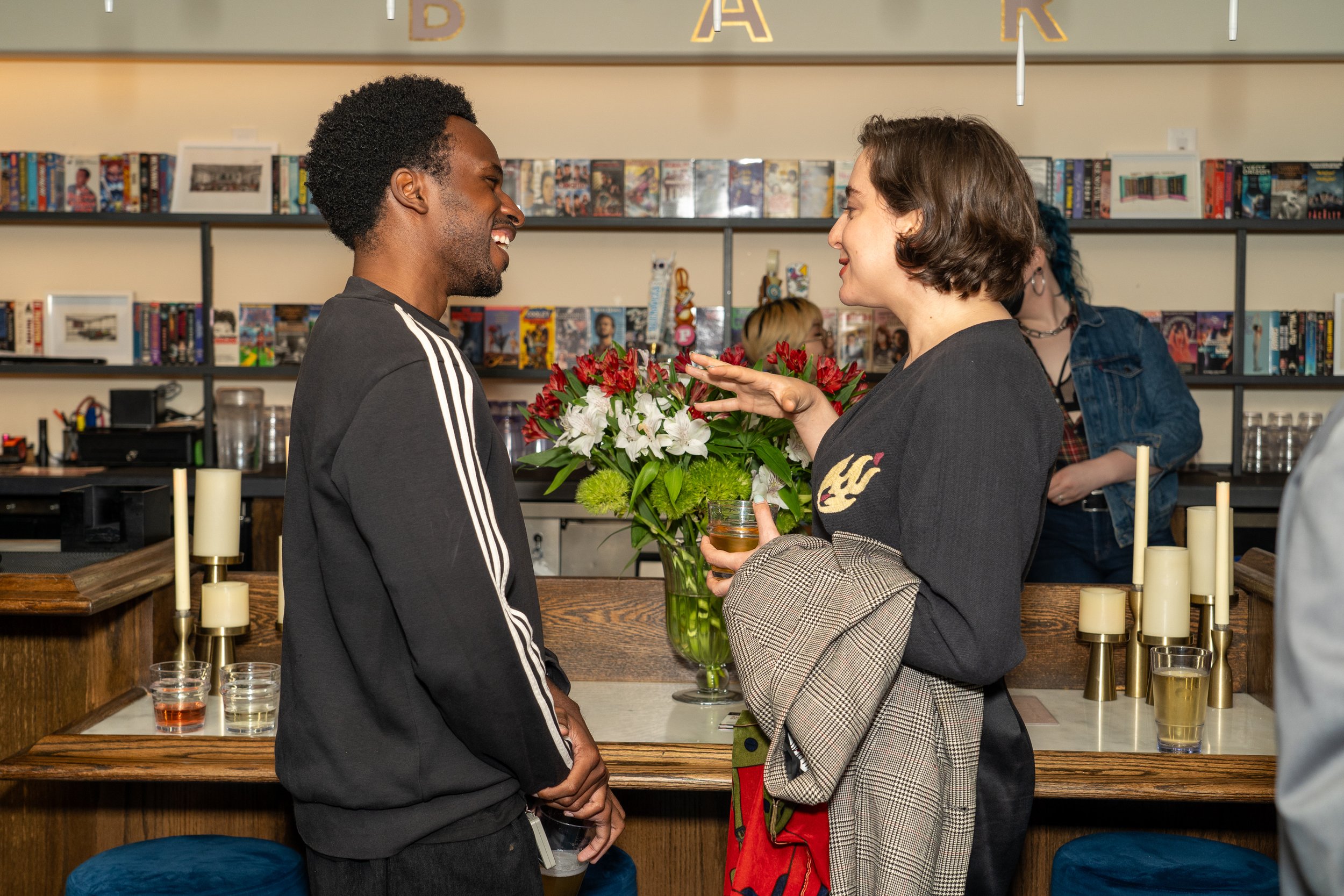  Two guests in animated conversation at the bar during the Familiar Touch preview screening in Los Angeles. 